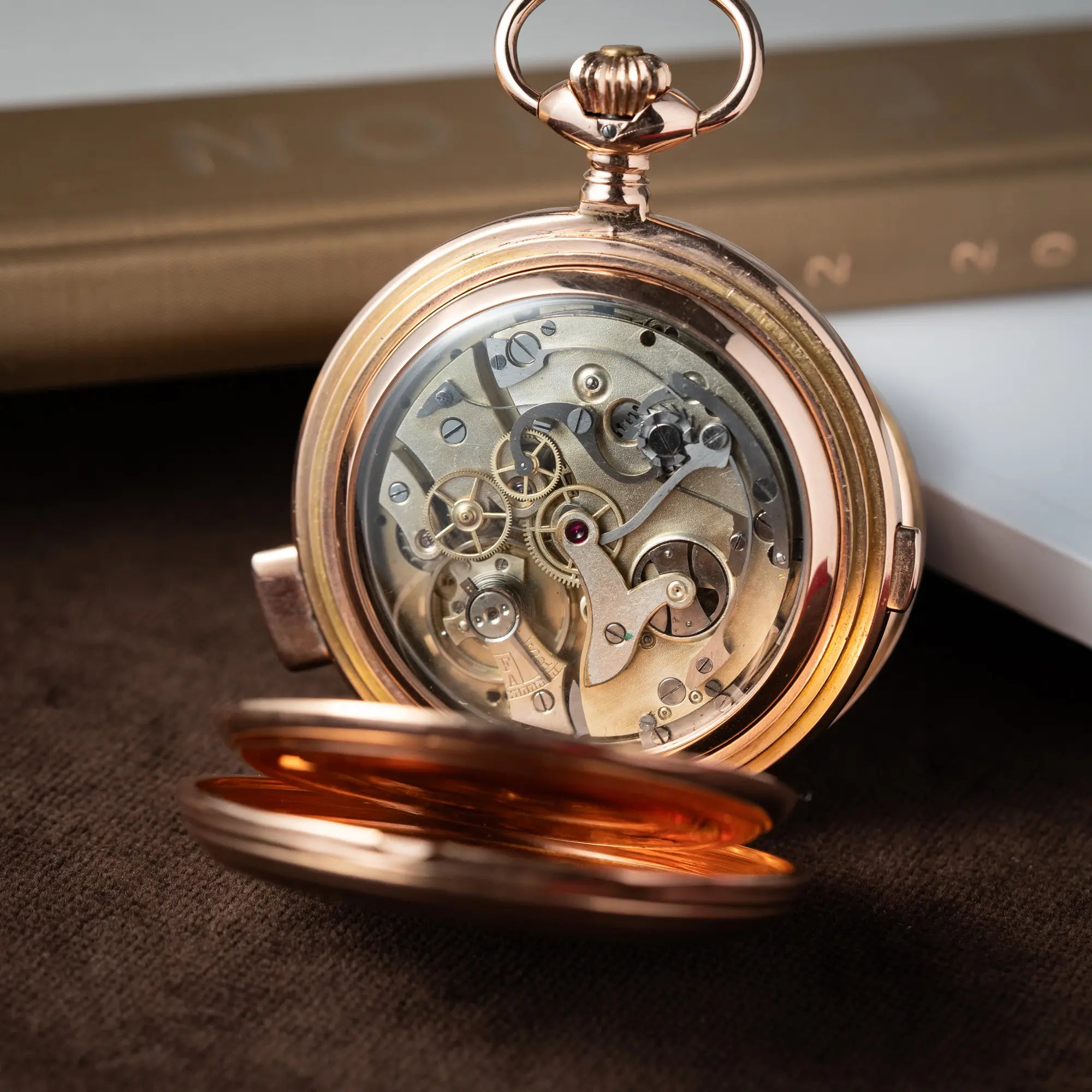 Produktfotografie zeigt das Handaufzug-Uhrwerk von der Vollkalender Taschenuhr aus 14 Karat Roségold mit viertel Stunden Repetition und Mondphase-Anzeige bei 6 Uhr