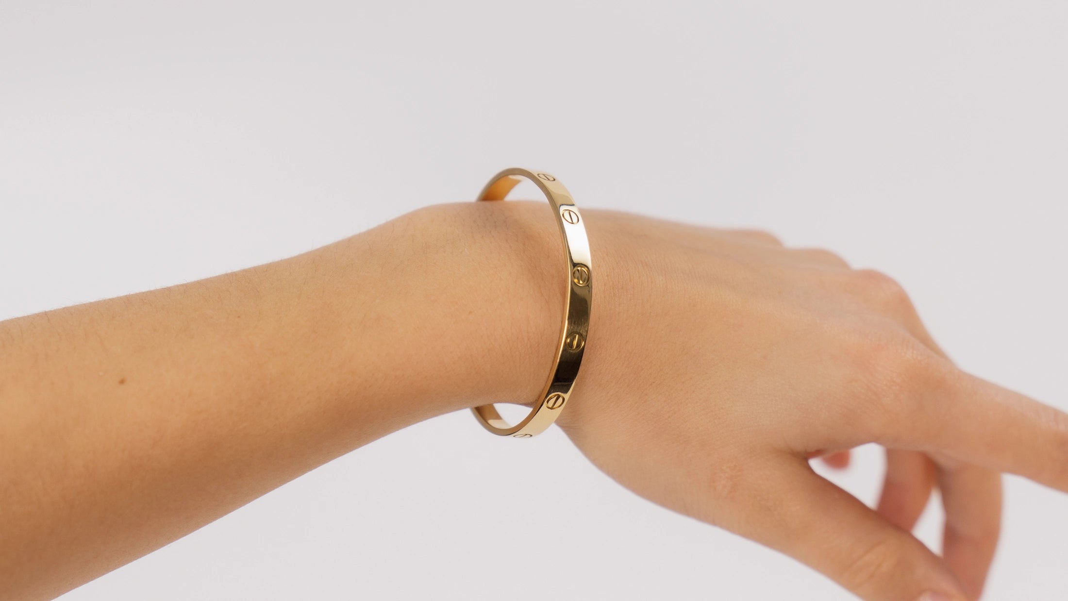 Frau präsentiert ein Cartier Love Bracelet aus Gelbgold an Ihrem Arm