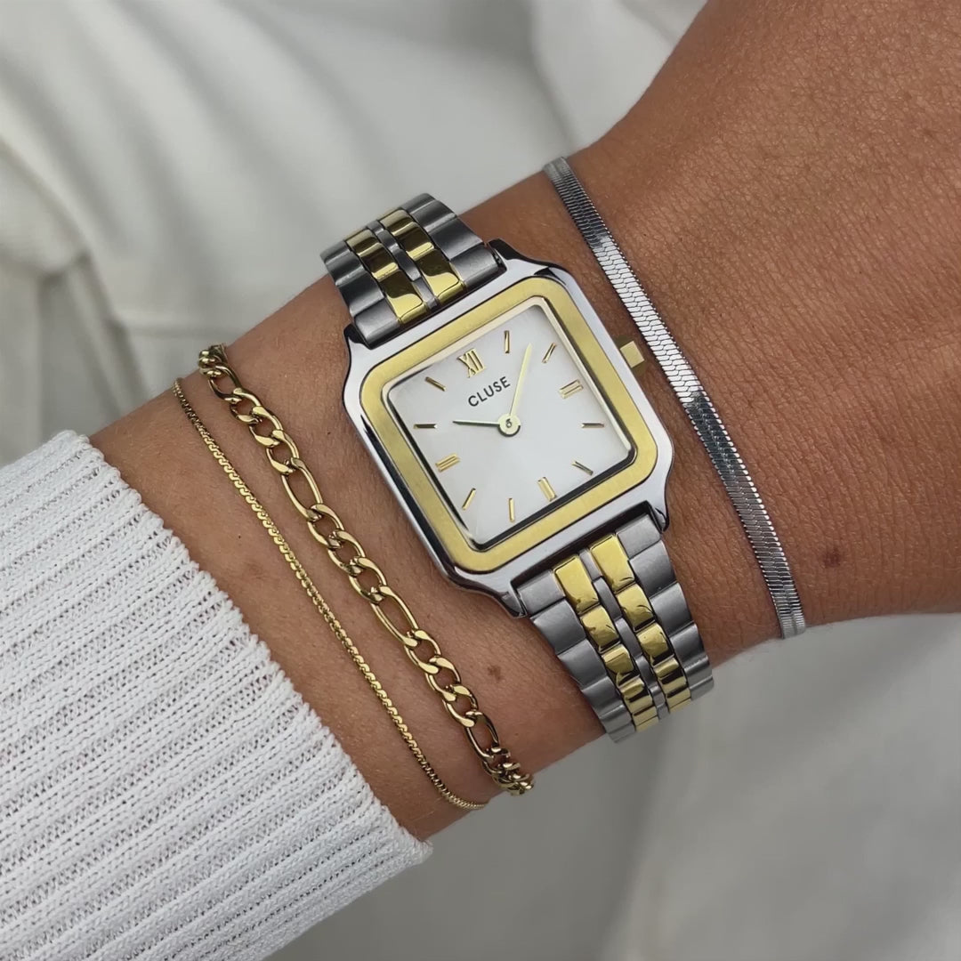 Frau trägt die Cluse Stahl-Uhr "Gracieuse Petite" in Stahl-Gold-Optik (bicolor) mit weißem Zifferblatt an ihrem Handgelenk und präsentiert diese mit einem Wrist-Roll