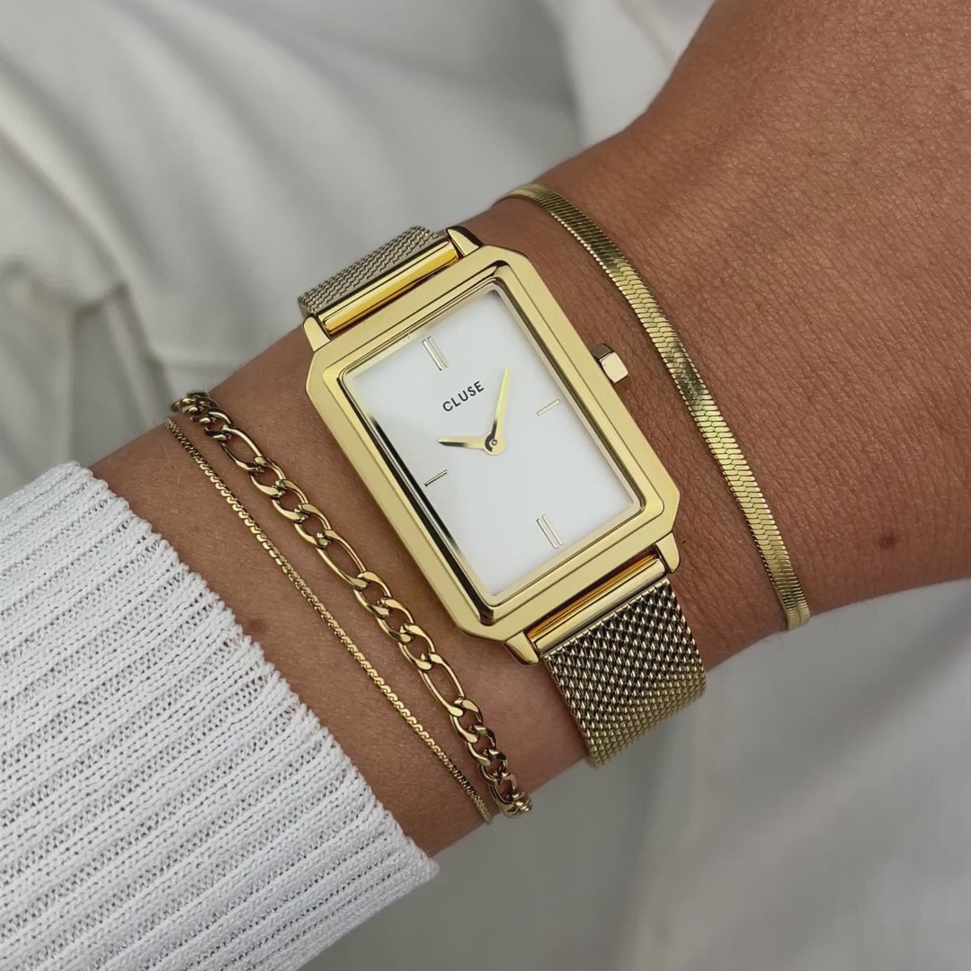 Frau trägt die Cluse Stahl-Uhr "Fluette" mit gelbgoden-farbigem Gehäuse und weißem Zifferblatt an Ihrem handgelenk und präsentiert diese mit einem Wrist-Roll