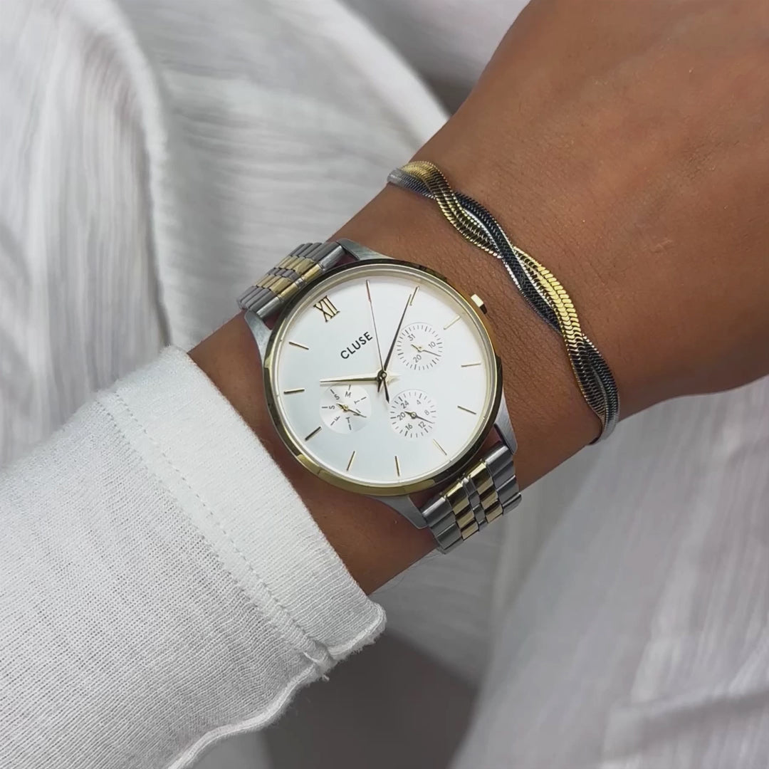 Frau präsentiert die Cluse Stahl-Uhr "Minuit Multifunction" in Bicolor-Optik (Stahl-Gelbgold) mit silberfarbenem Zifferblatt und drei Sub-Dials mit einem Wrist-Roll