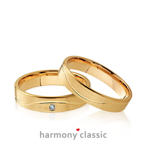 Produktfotografie des Trauringpaars Harmony Classic in Gelbgold mit Diamanten und Verzierungen im Damenring