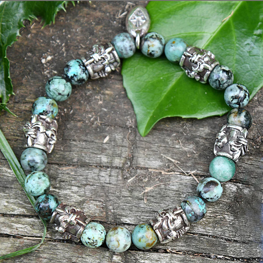 Produktfotografie des Elfcraft Armbands mit Kugeln aus afrikanischem Türkis und silbernen Hülsen, die mit Lilien-Details verziert sind