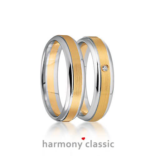 Produktfotografie des Trauringpaars Harmony Classic in Weißgold mit einem goldenen, mittigen Streifen, mit Diamant im Damenring