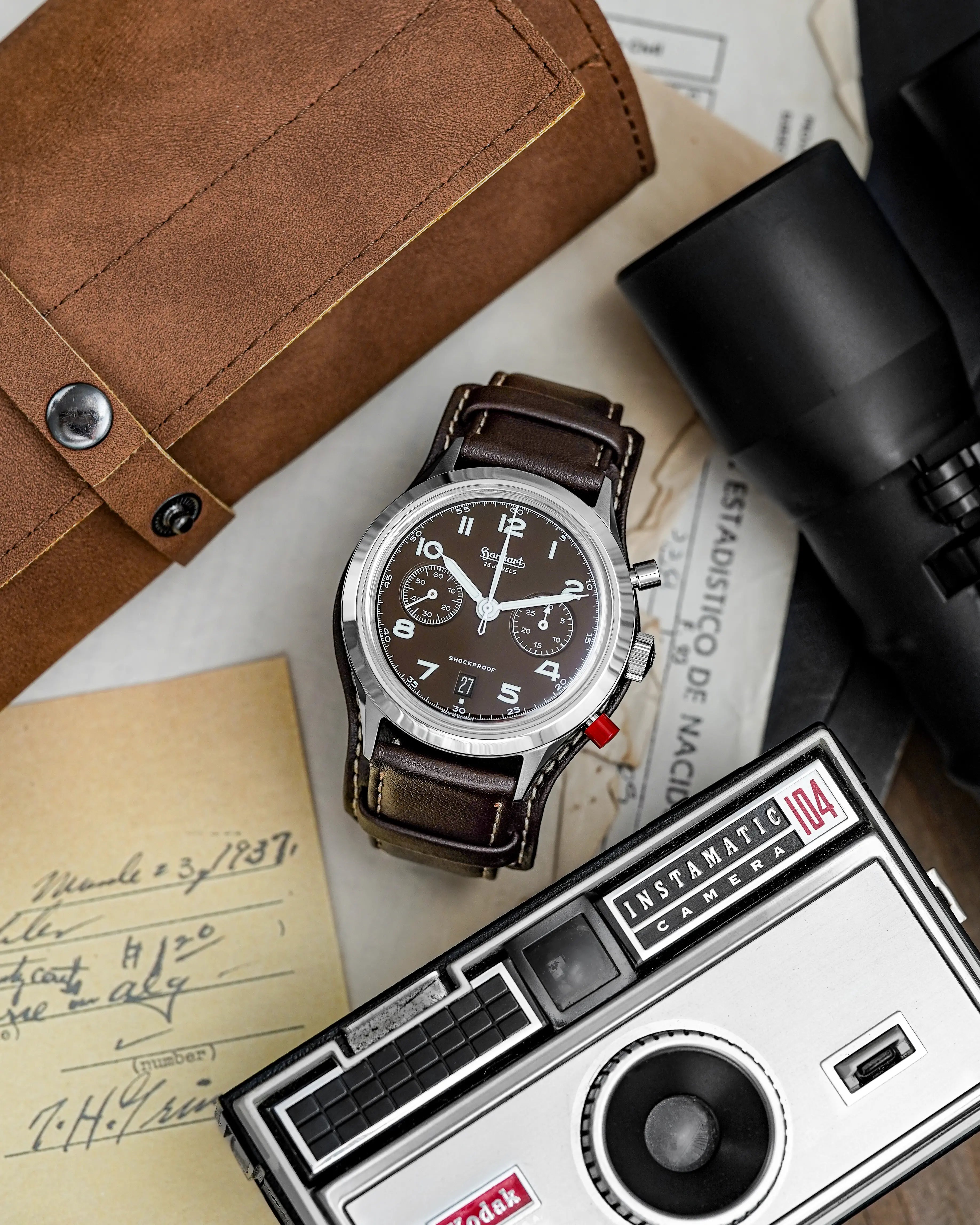 Produktfotografie der Hanhart 417 ES Mokka Limited Edition mit einem braunem Zifferblatt an einem passenden braunem Lederband mit Unterlage