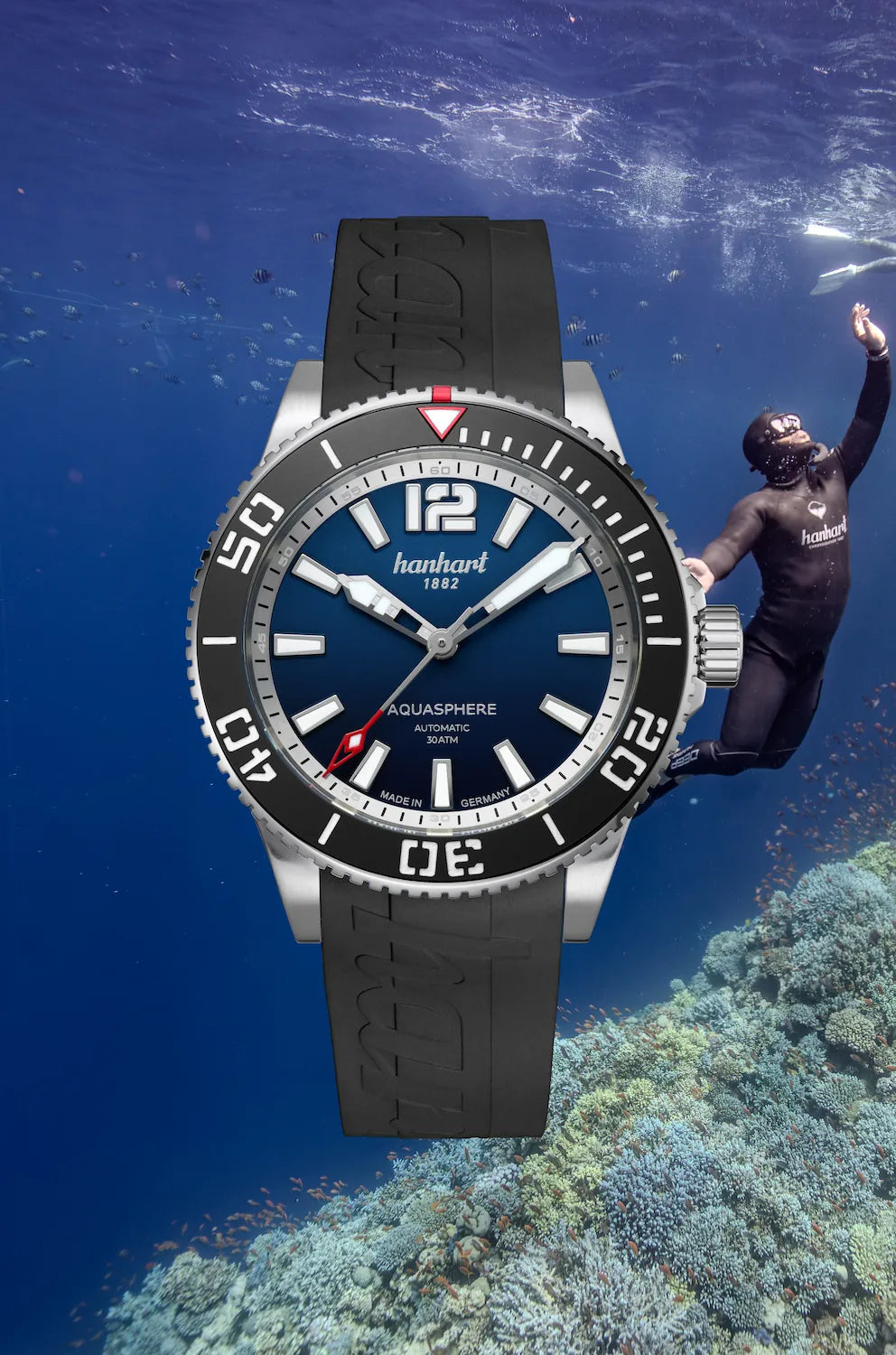 Produktfotografie zeigt die frontale Ansicht der Hanhart Aquasphere mit dem blau-schwarz verlaufenden "Ocean Fade"-Zifferblatt und schwarzem  Keramik-Inlay auf der Lünette am schwarzen Kautschuk-Armband mit einem Taucher im Meer als Hintergrund