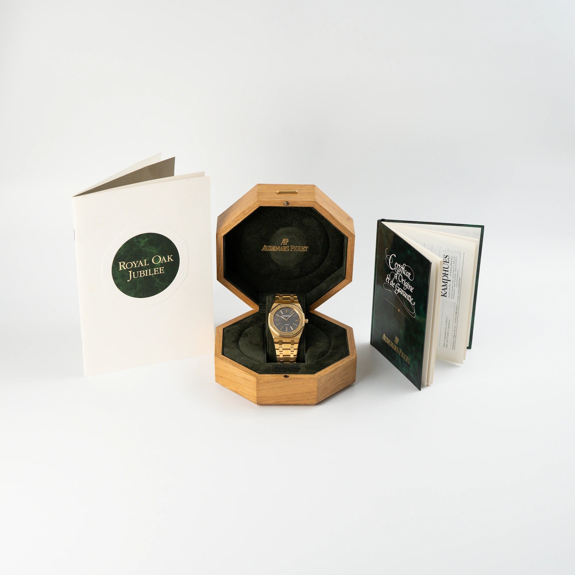 Audemars Piguet Royal Oak Jumbo 14802BA Jubilee in Gelbgold liegt in der Uhrenbox aus Holz und daneben stehen Booklet und Zertifikat der Uhr