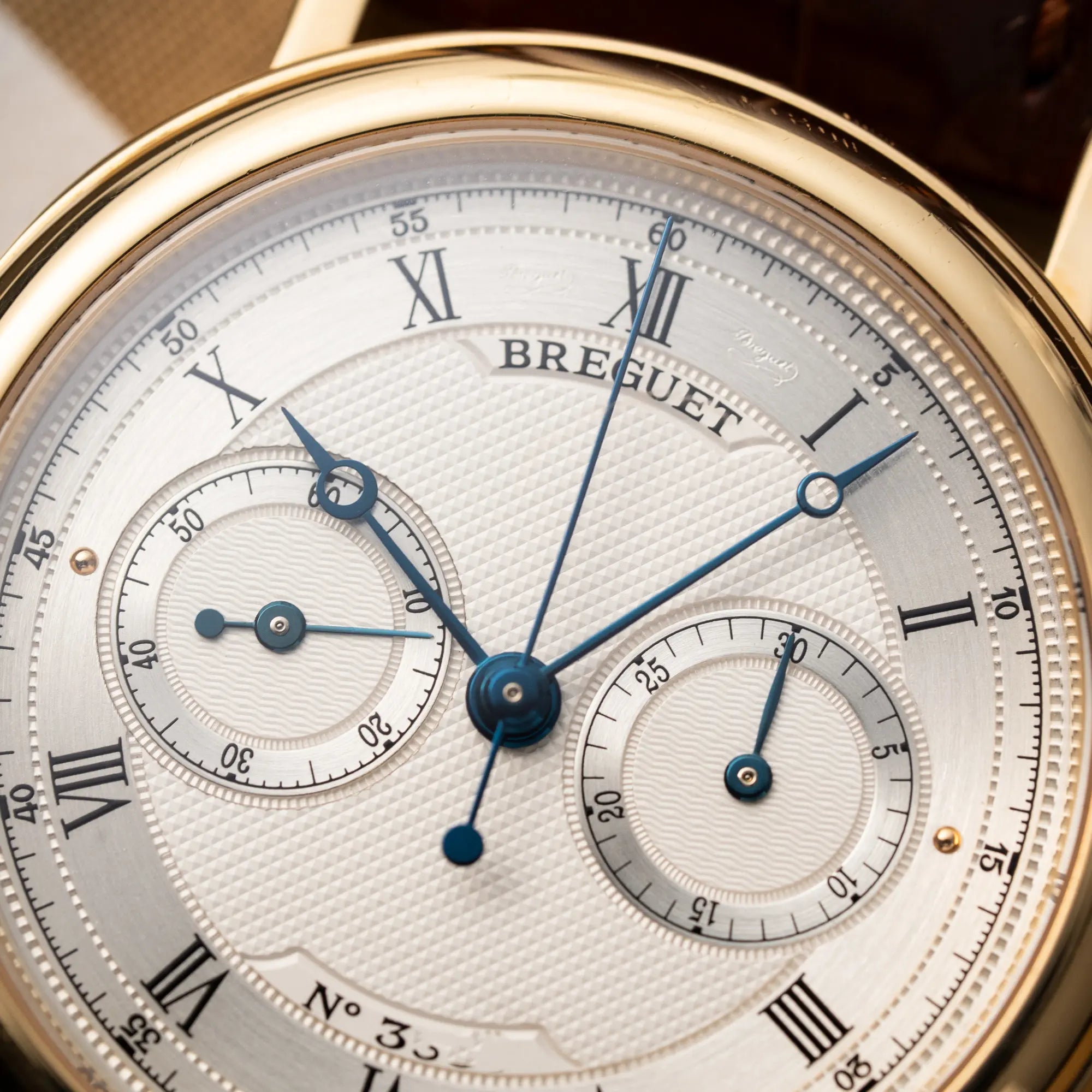 Detailaufnahme der Breguet Classique Chronograph der Referenz 5237 in Gelbgold mit silbernem guillochiertem Zifferblatt am braunem Lederband 