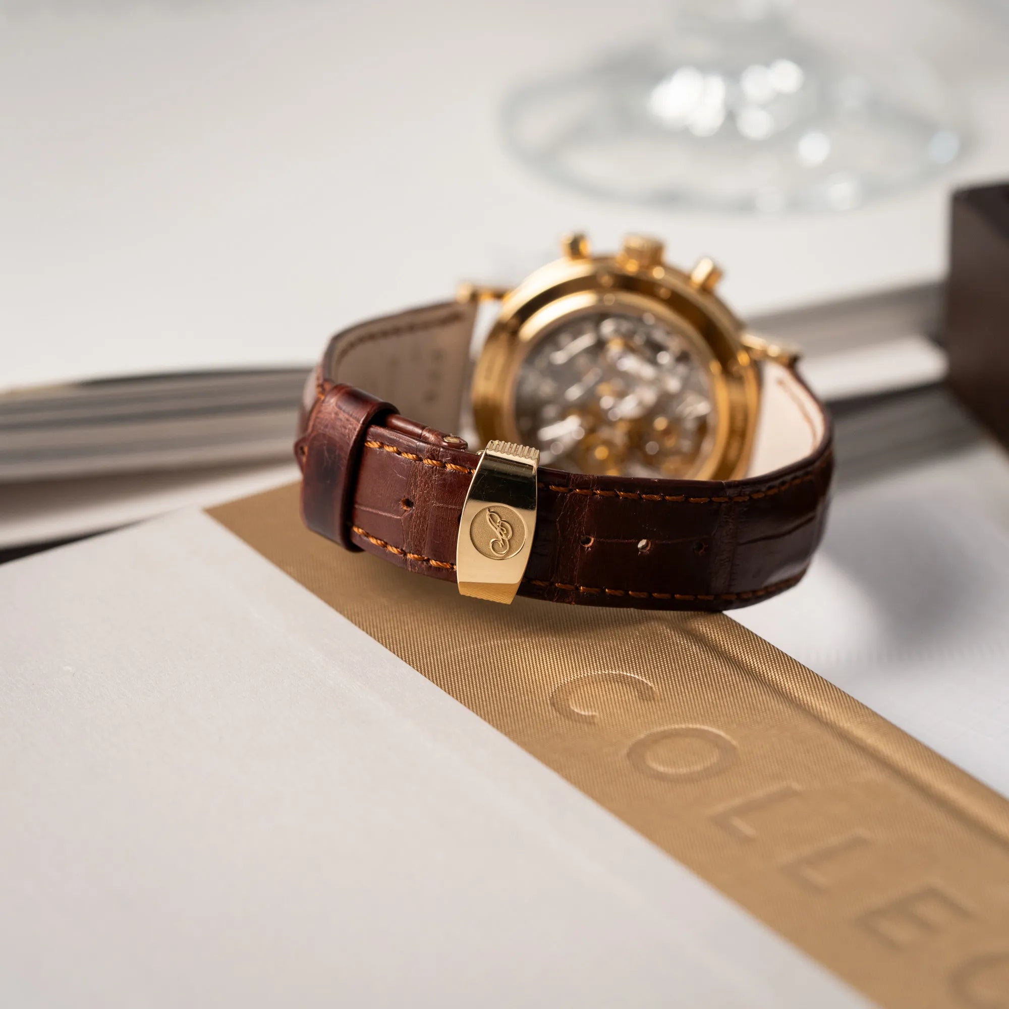Produktfotografie des Breguet Classique Chronograph der Referenz 5237 in Gelbgold mit silbernem guillochiertem Zifferblatt am braunem Lederband  zeigt die gelbgoldene Faltschliesse mit Breguet-Logo