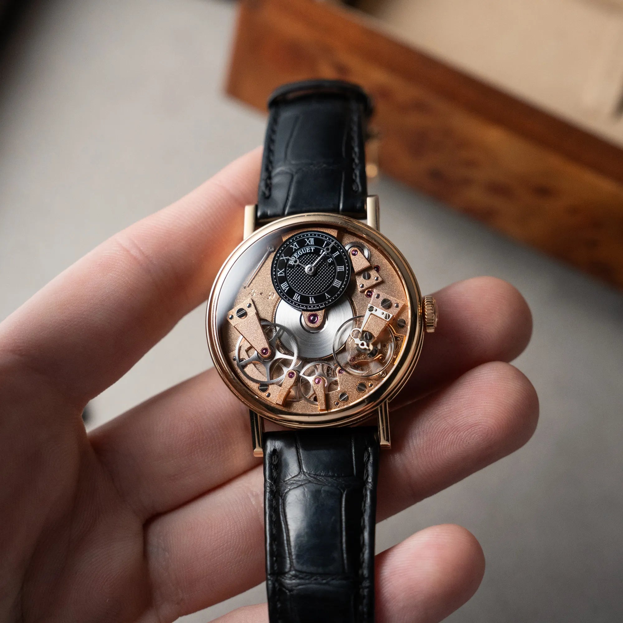 Mann hält die klassische Breguet Tradition  Armbanduhr mit Rosegold-Gehäuse und schwarzem Zifferblatt in der Hand