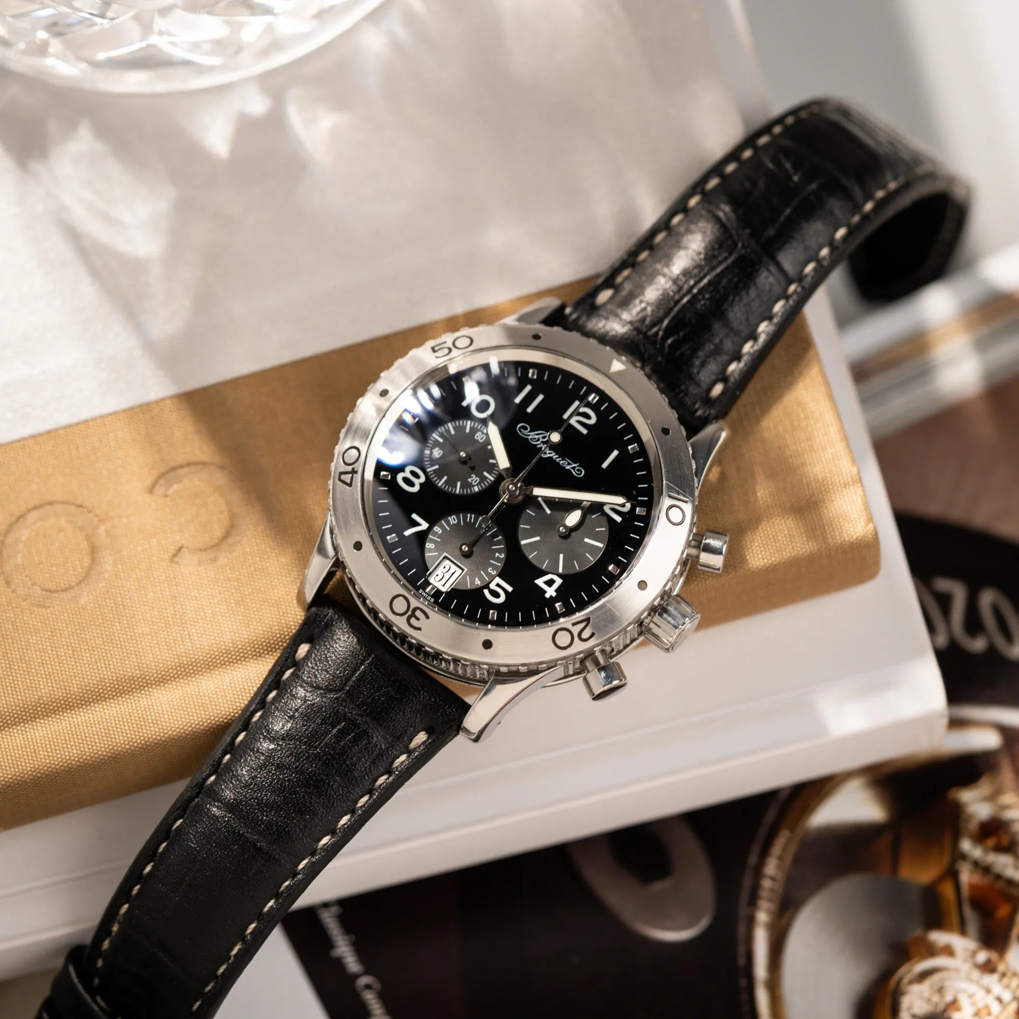 Produktfotografie als Titelbild für die Breguet Type XX Aéronavale Transatlantique der Referenz 3820ST mit schwarzem Lack-Zifferblatt am originalen schwarzen Breguet-Lederband