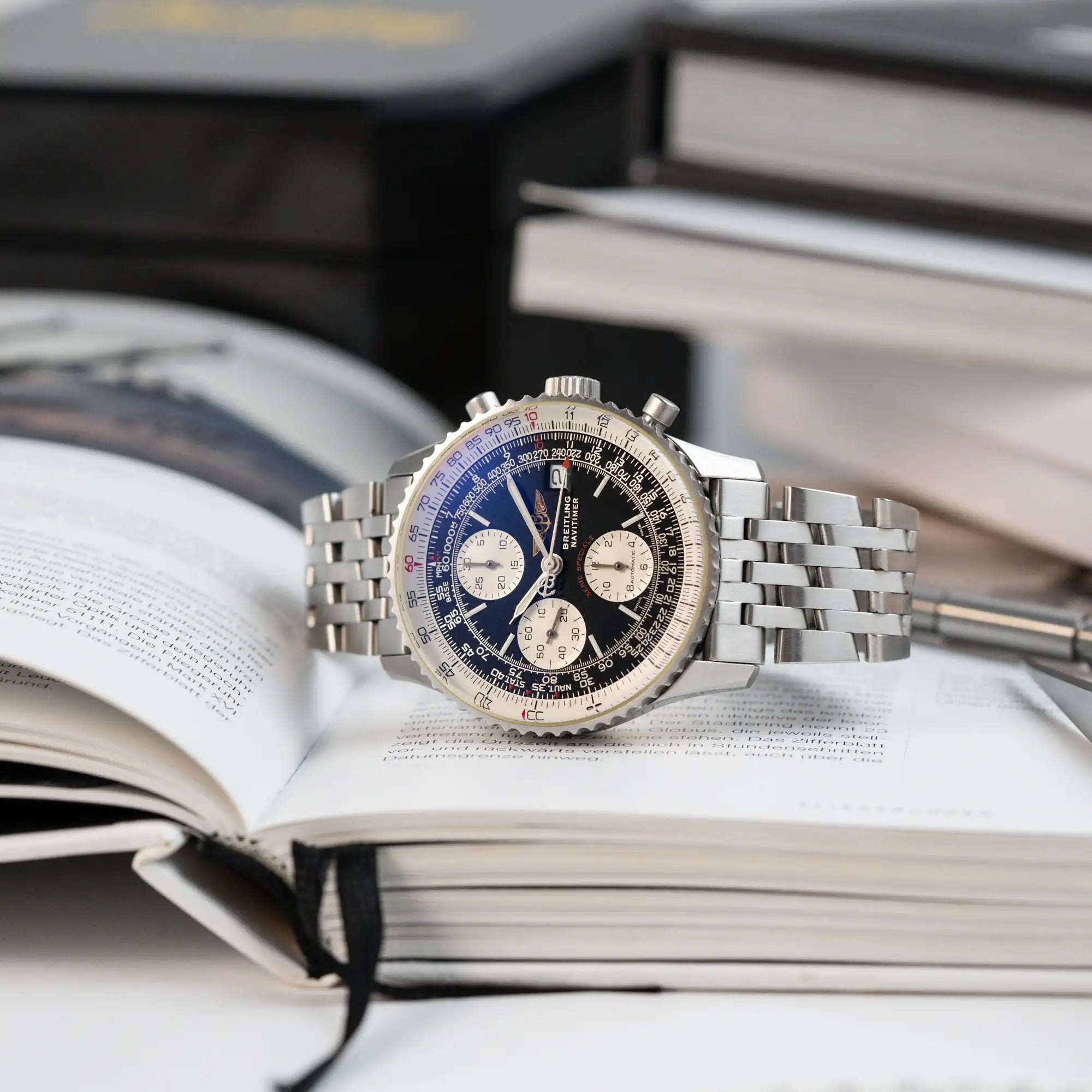 Produktfotografie der Breitling Navitimer Armbanuhr "Fighters Edition" mit der Referenz A13330, während die auf dem seitlichen Gehäuse liegt