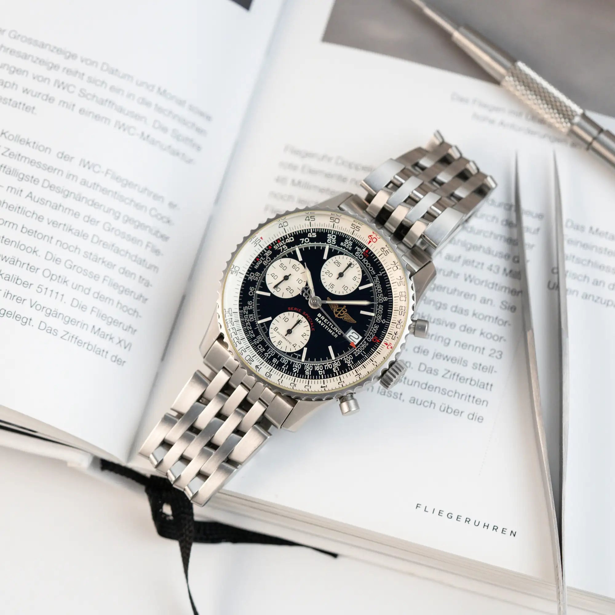 Produktfotografie der Breitling Navitimer Armbanuhr "Fighters Edition" mit der Referenz A13330 auf einem Buch über Fliegeruhren