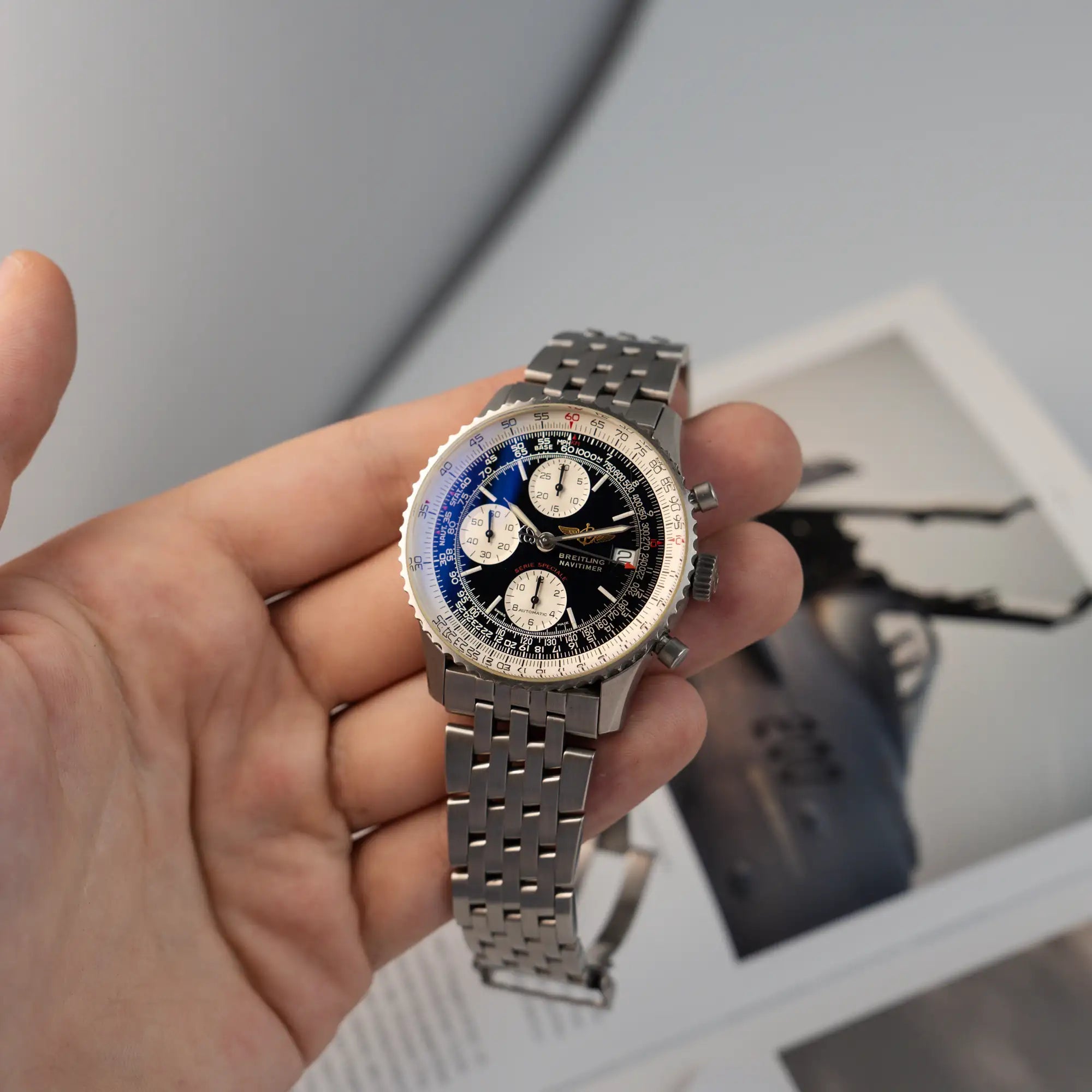 Mann präsentiert die Breitling Navitimer Fighters Edition A13330 und hält die Armbanduhr in seiner Hand