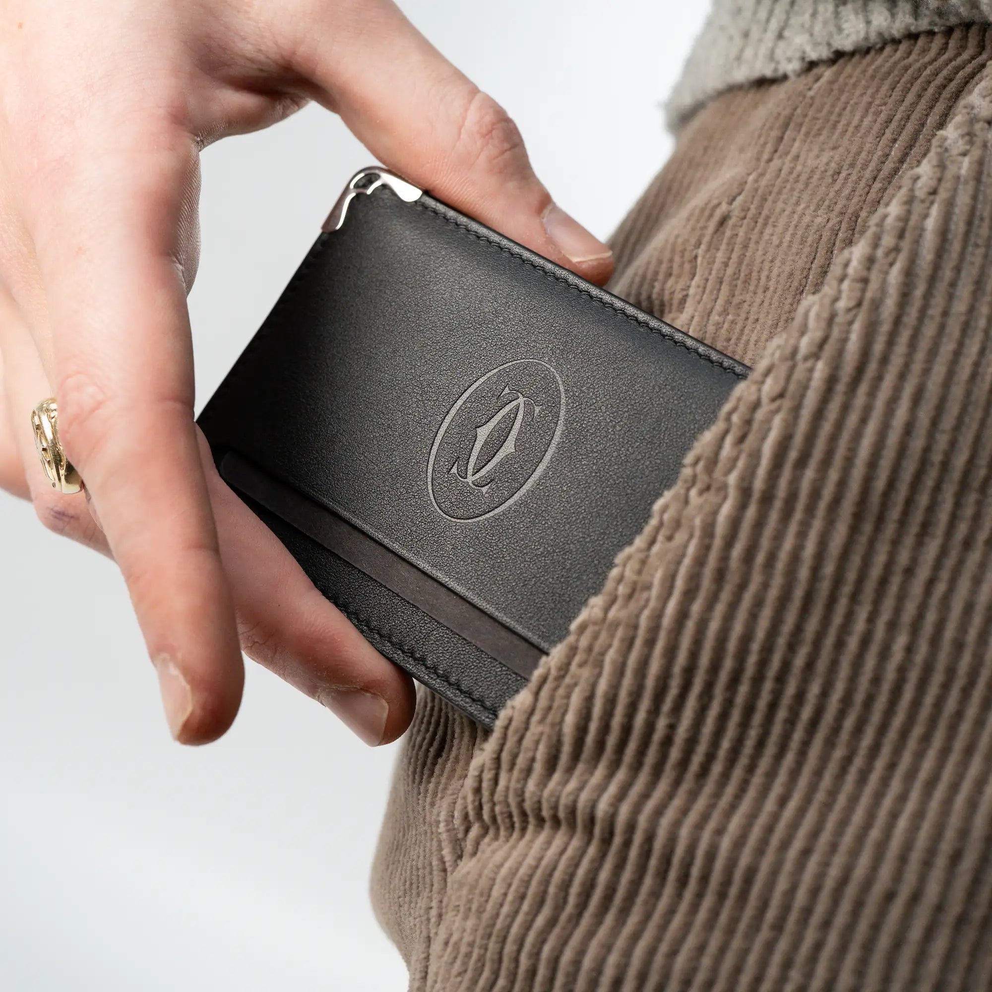 Mann zieht den schwarzen Cartier Cardholder aus seiner Hosentasche