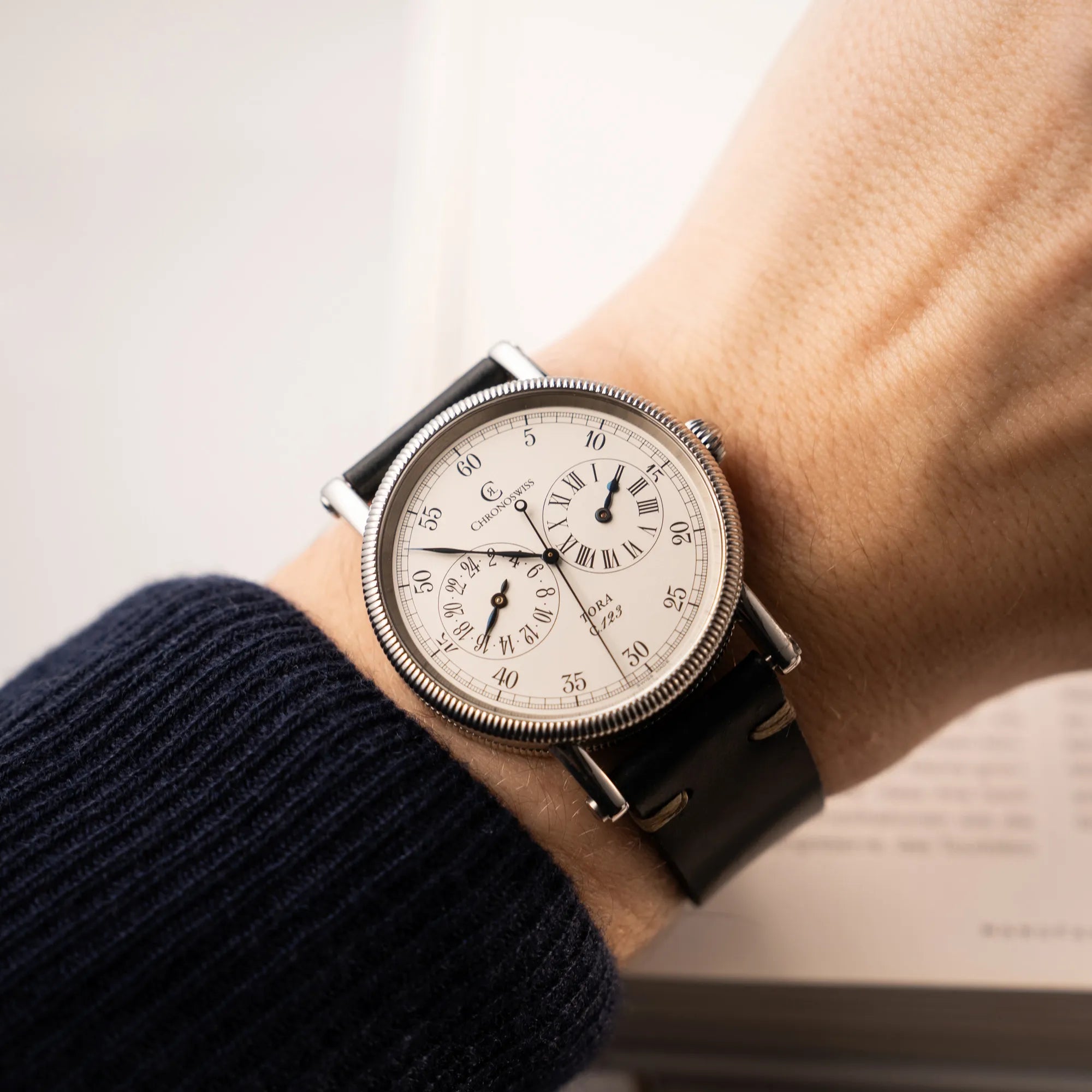 Wristshot mit der Chronoswiss Regulator Tora C123 mit weißem Zifferblatt mit zwei symmetrisch angeordneten Hilfszifferblättern mit römischen Indizes