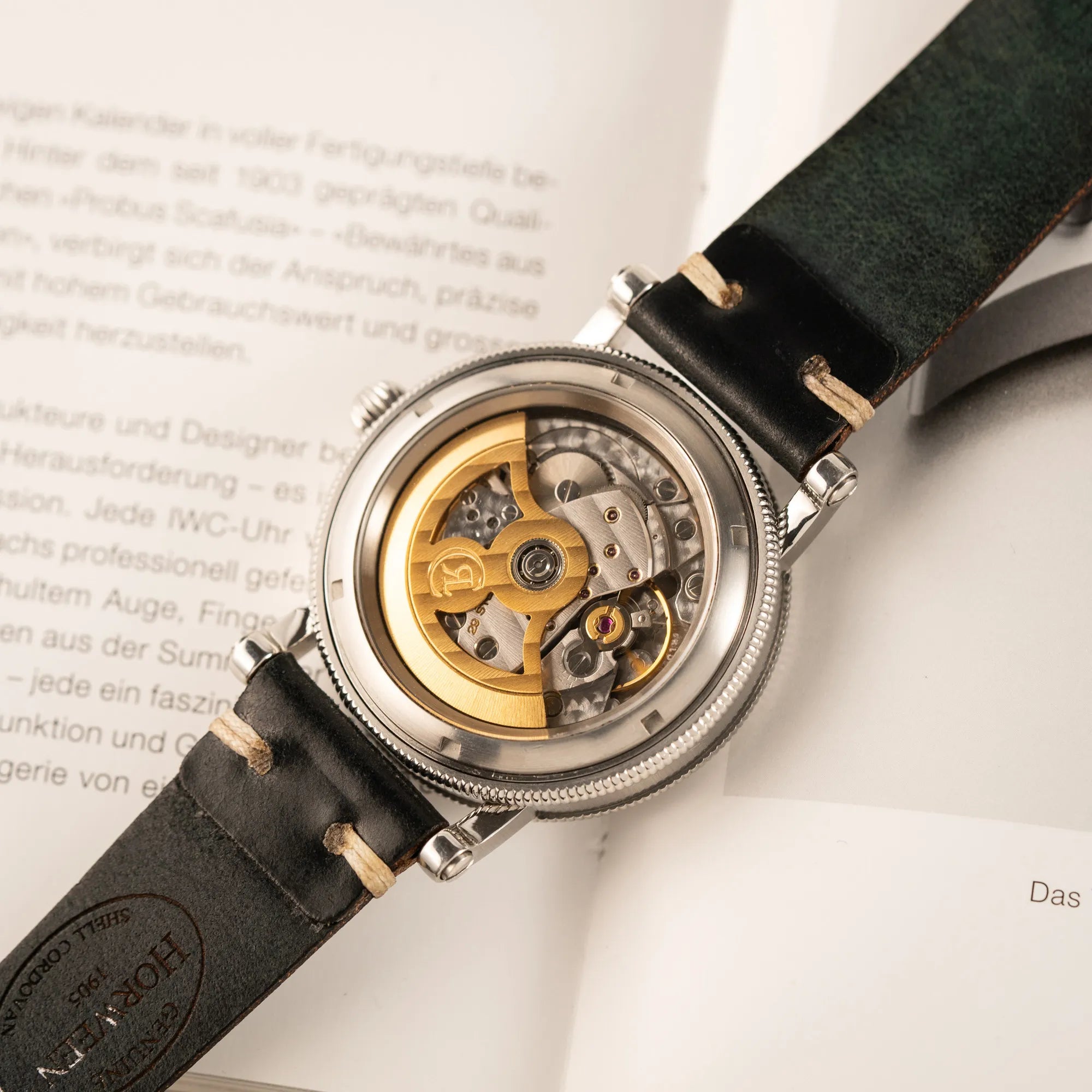 Produktfotografie der Chronoswiss Regulator Tora C123 mit weißem Zifferblatt mit zwei symmetrisch angeordneten Hilfszifferblättern mit römischen Indizes zeigt das Uhrwerk durch den Gehäuseboden aus Sichtglas
