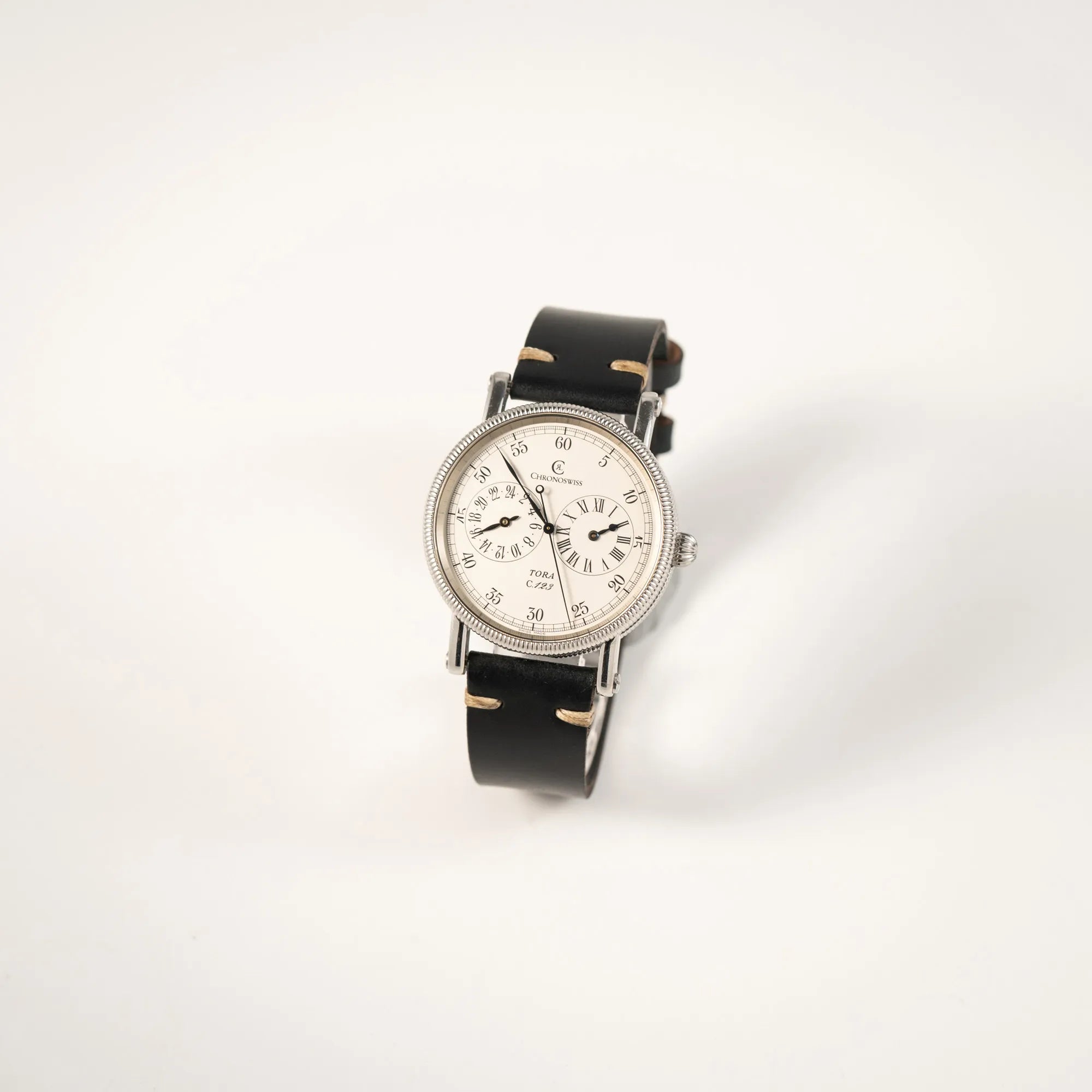 Leicht schräge Ansicht der Chronoswiss Regulator Tora C123 mit weißem Zifferblatt mit zwei symmetrisch angeordneten Hilfszifferblättern mit römischen Indizes