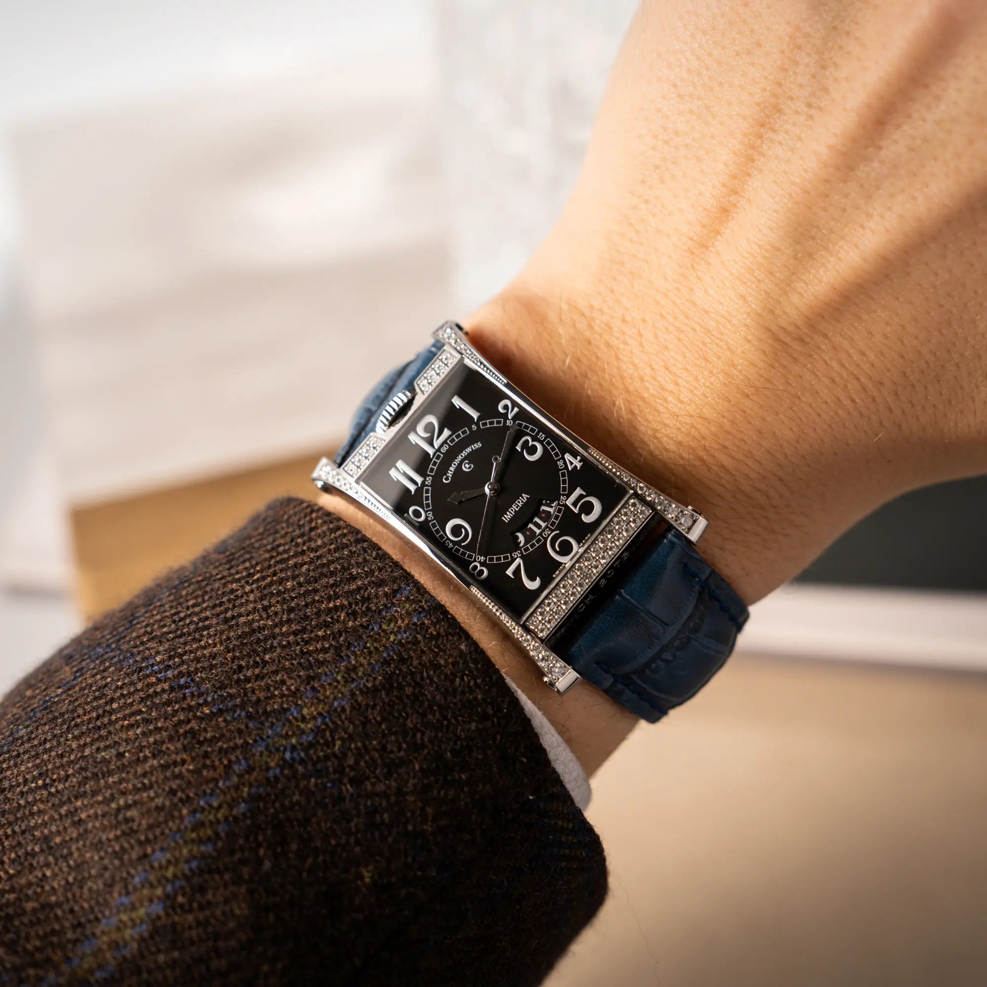 Wristshot mit der Chronoswiss Imperia Constanze mit diamantbesetzten-Stahlgehäuse mit schwarzem Zifferblatt an einem petrol-blauem Lederband
