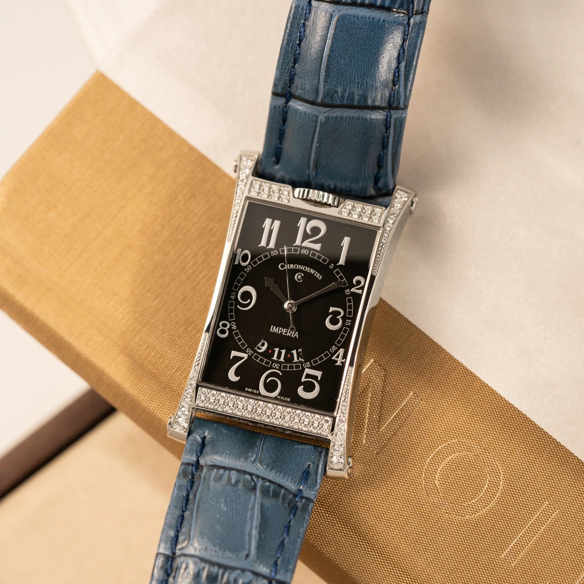 Produktfotografie der Chronoswiss Imperia Constanze mit diamantbesetzten-Stahlgehäuse mit schwarzem Zifferblatt an einem petrol-blauem Lederband