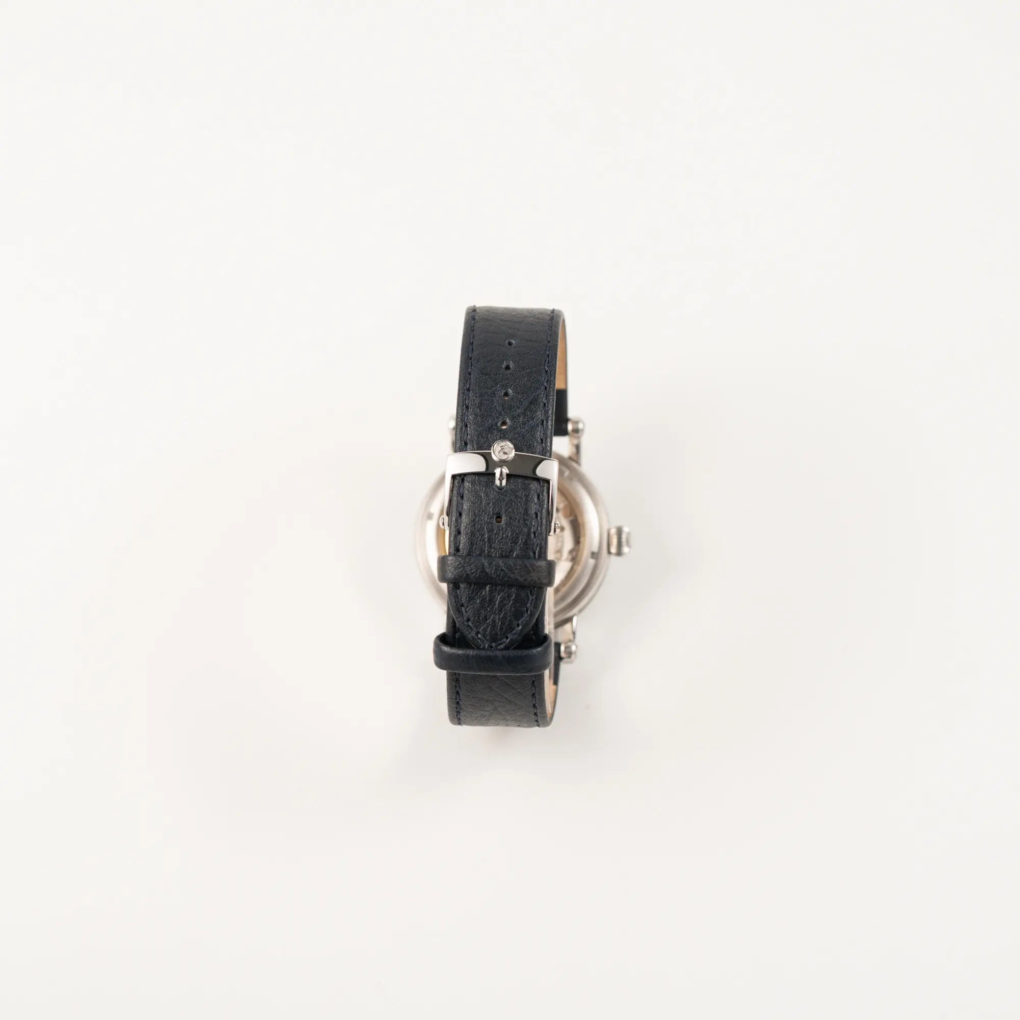 Blick auf das dunkelblaue Lederband und die Dornschliesse der Chronoswiss Klassic Luna Mondphase CH9323 mit silbernem, guillochiertem Zifferblatt mit Kalenderanzeige auf 12 Uhr und einer Mondphase-Anzeige bei 6 Uhr