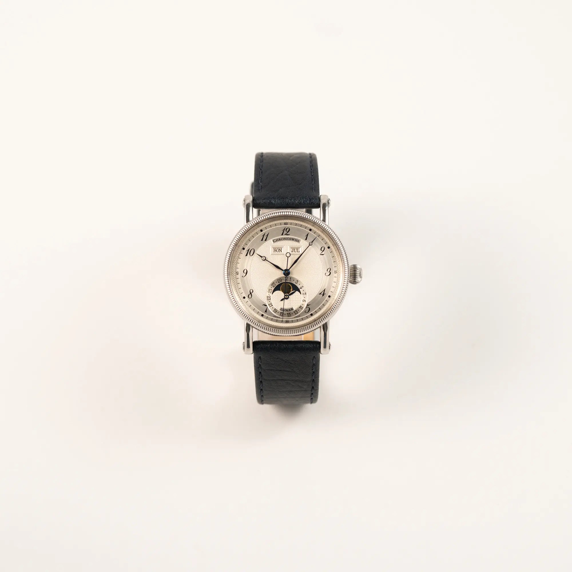 Frontale Ansicht der Chronoswiss Klassic Luna Mondphase CH9323 mit silbernem, guillochiertem Zifferblatt mit Kalenderanzeige auf 12 Uhr und einer Mondphase-Anzeige bei 6 Uhr