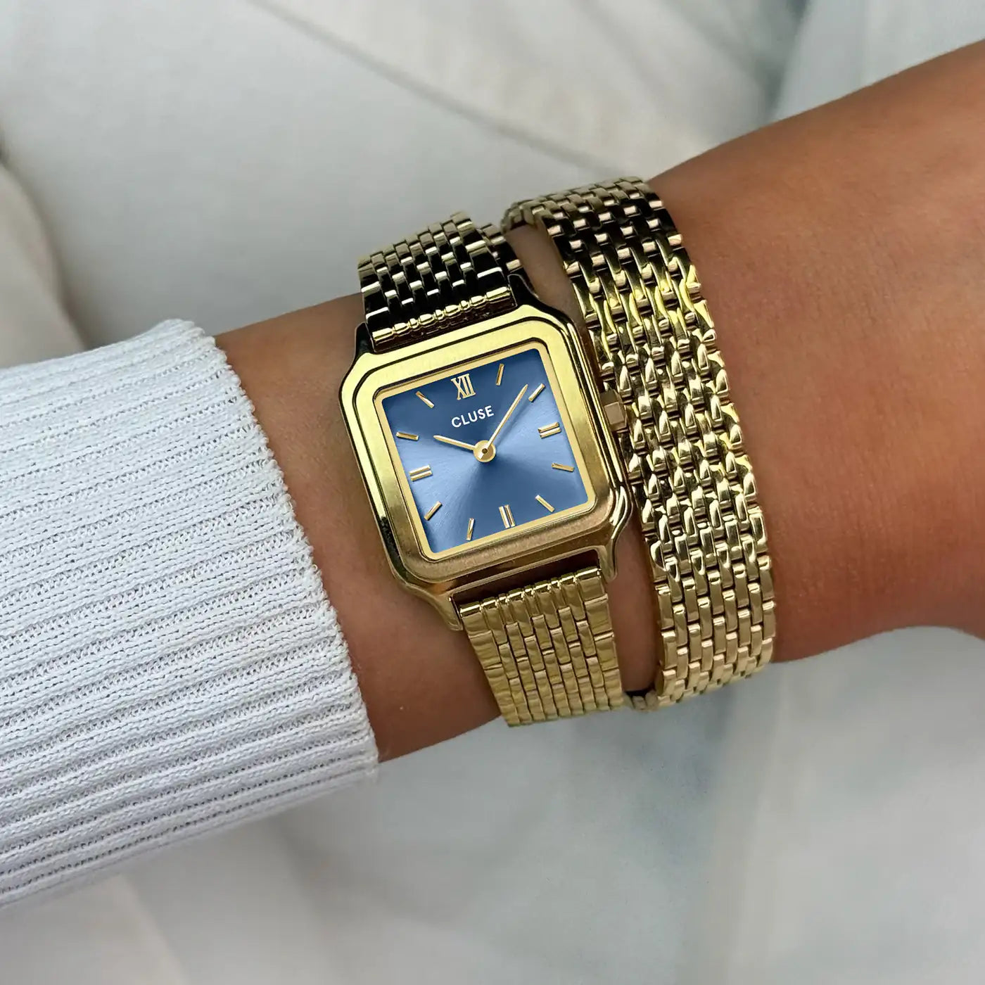 Wristshot mit der goldfarbenen Cluse Gracieuse Petite Damenuhr mit rechteckigem Gehäuse und blauem Zifferblatt an einem feingliedrigen Doppel-Armband