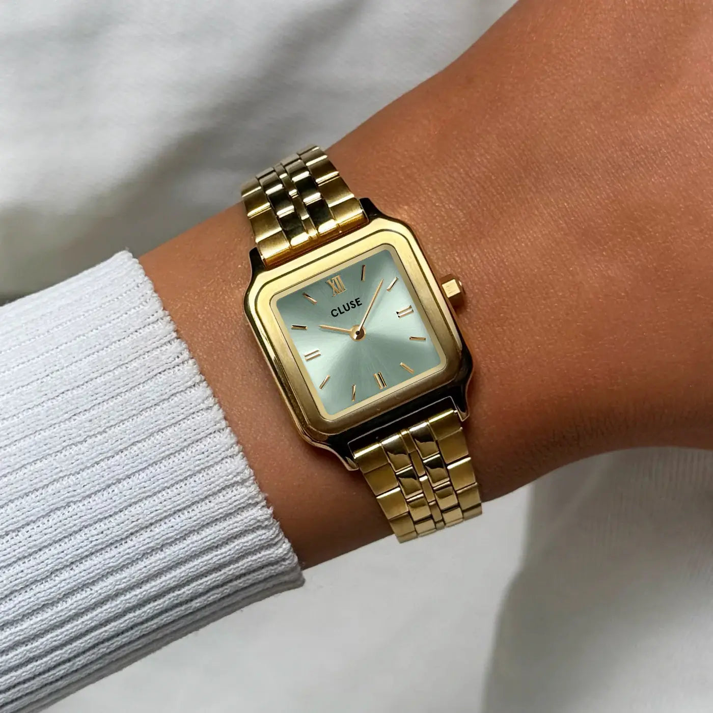 Wristshot mit der der goldfarbenen Cluse Gracieuse Petite Damenuhr mit rechteckigem Gehäuse und salbeigrünem Zifferblatt