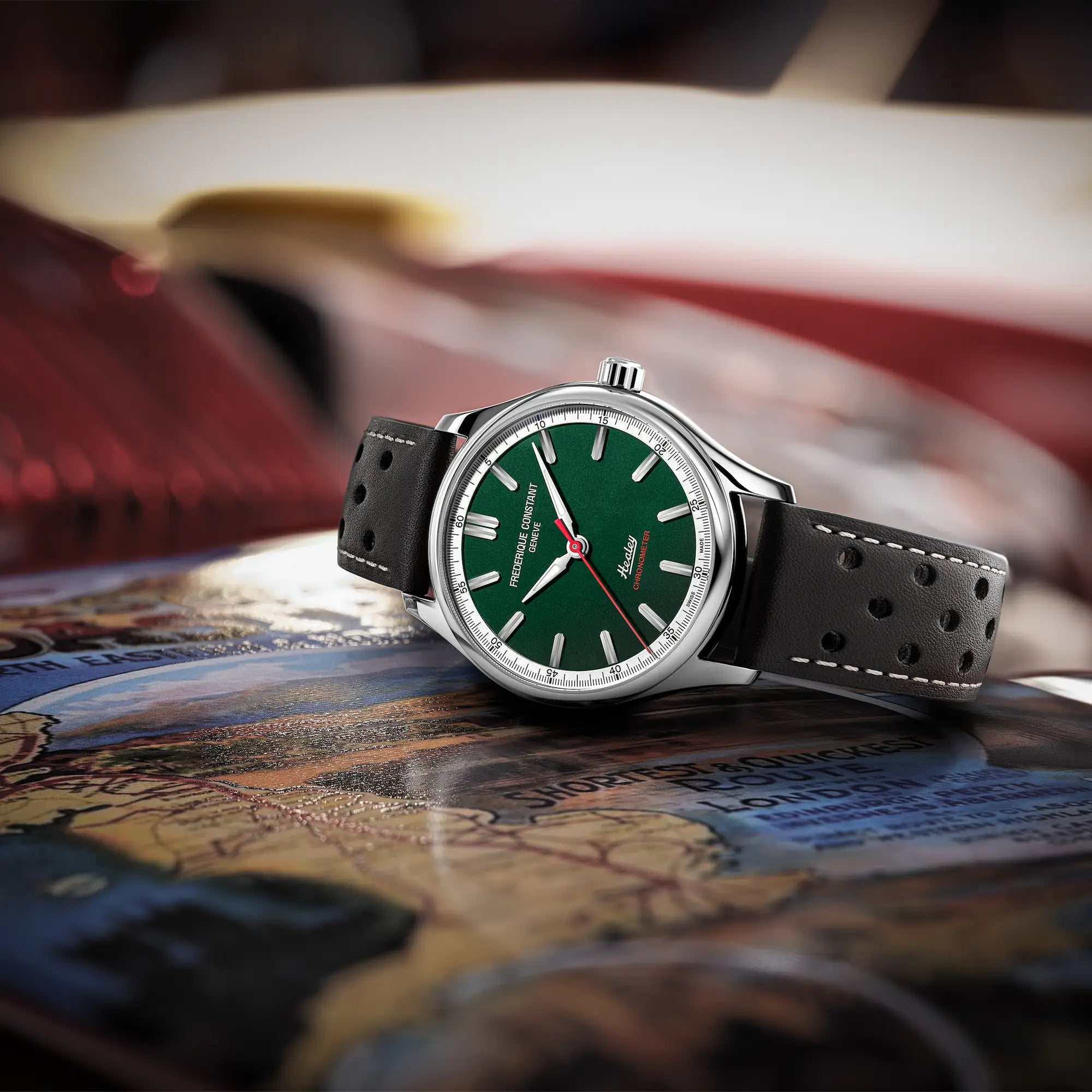 Produktfotografie der "Vintage Rally Healey" Uhr von Frederique Constant aus der Classics Kollektion mit einem dunkelgrünem Zifferblatt und einem braunen Lederarmband im Racing-Look, während die Uhr auf einem Buch mit einer Karte liegt