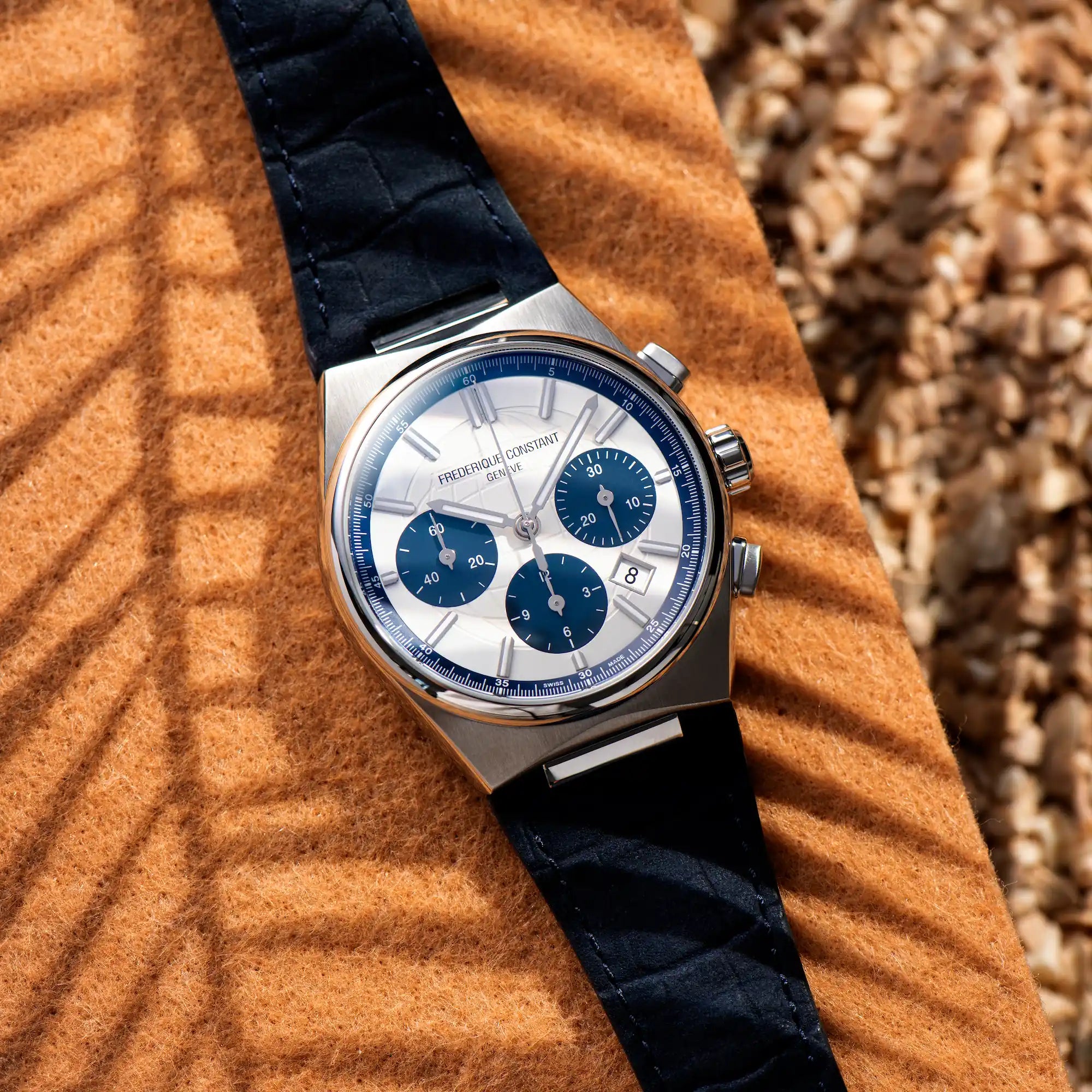 Sommerliche Produktfotografie des Highlight Chronographen von Frederique Constant mit einem weißen Zifferblatt und blauen Akzenten