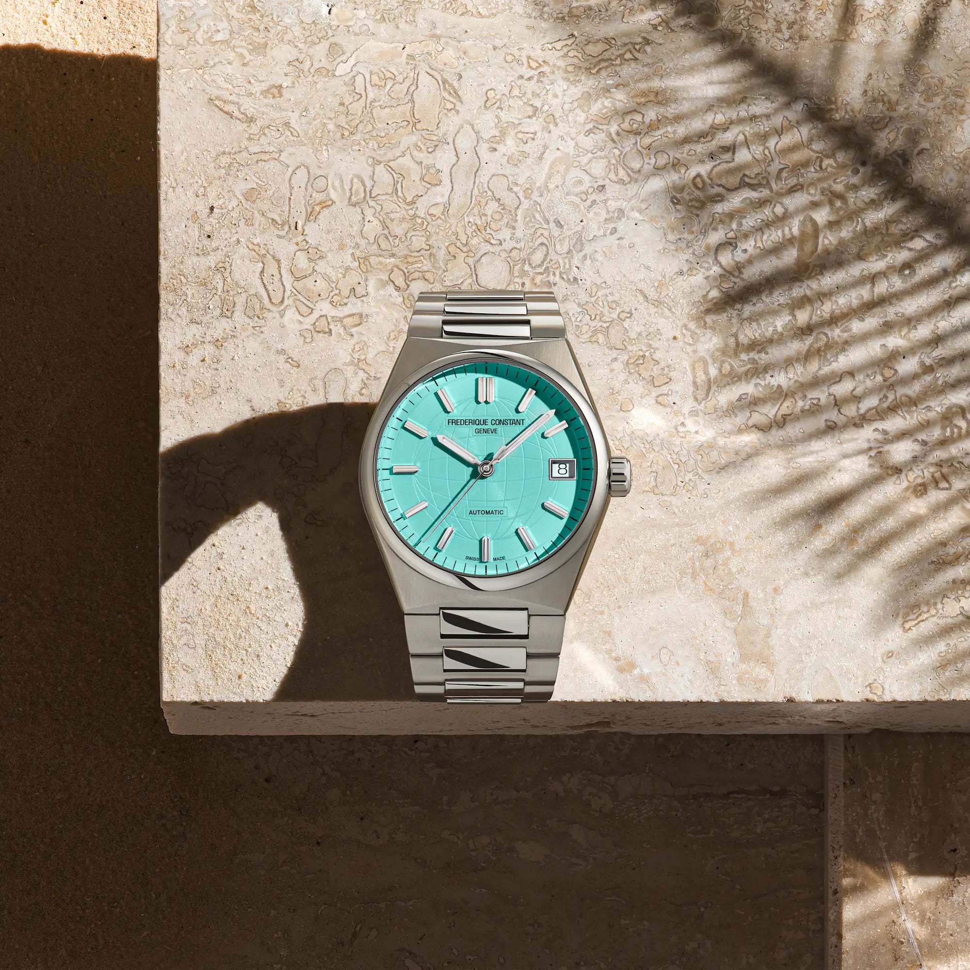 Produktfotografie der er Frederique Constant Uhr "Highlife Ladies Automatic" mit dem Tiffany-blauen Zifferblatt und Edelstahl-Gehäuse mit Blick auf das Uhrwerk (vor einem beigen Stein als Hintergrund)