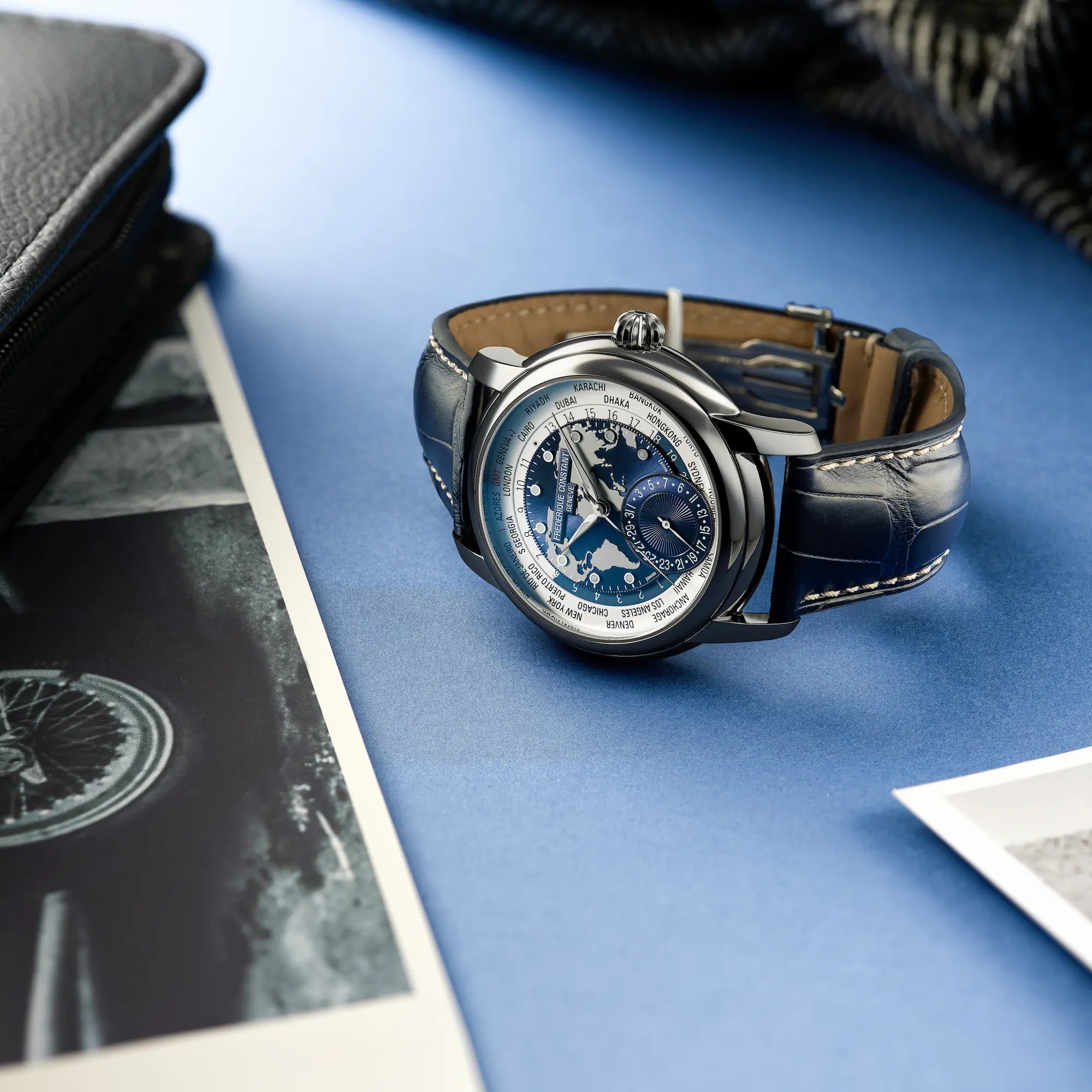 Produktfotografie des limitierten Classic Manufacture Worldtimers von Fredeique Constant mit dem weiß-blauen Weltkarten-Zifferblatt am dunkelblauen Lederband
