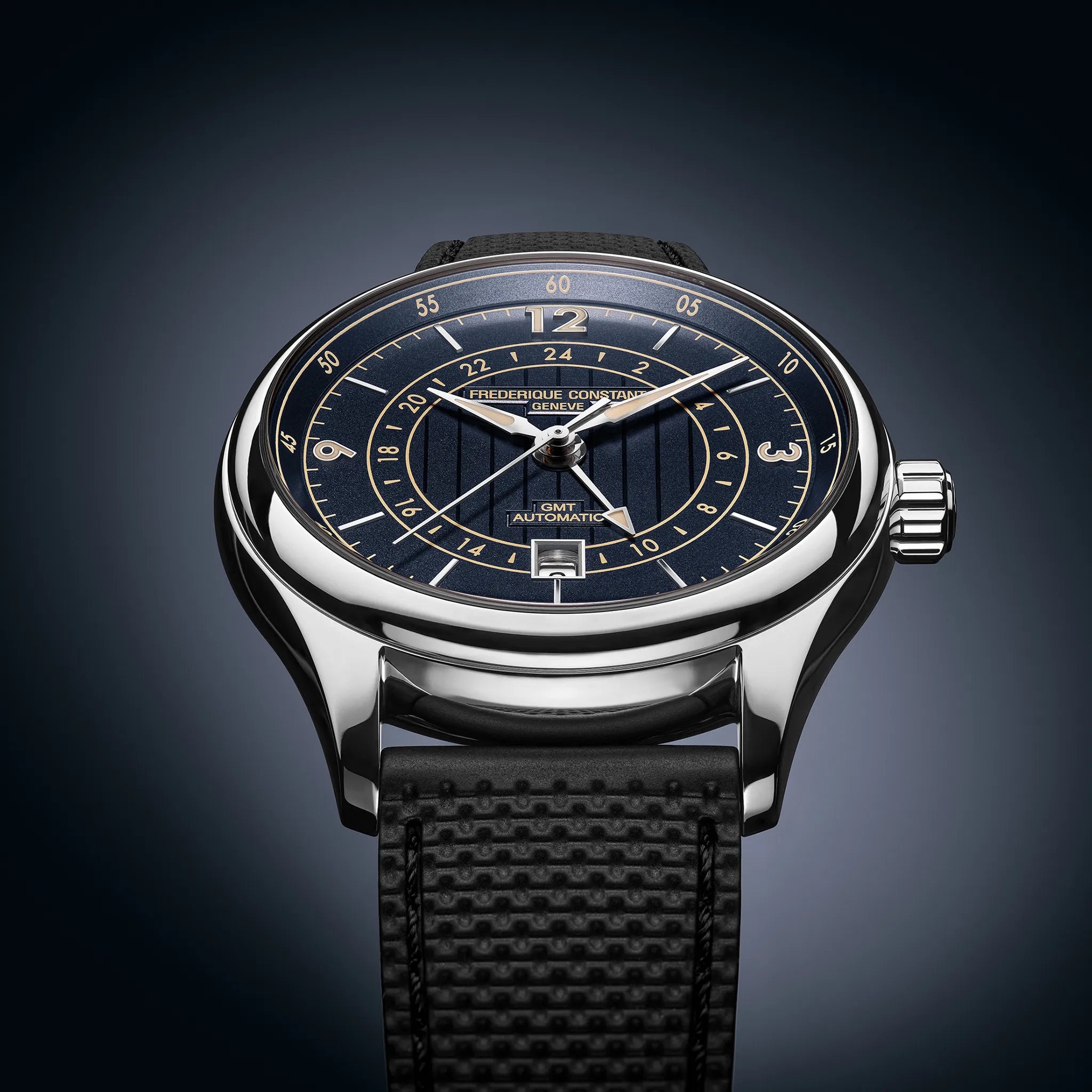 Produktfotografie mit schräger Ansicht von der Frederique Constant Runabout GMT Herrenuhr FC-350RN5B6 mit 42mm Edelstahl-Gehäuse, tiefblauem Zifferblatt mit Indizes im beigen Vintage-Look am schwarzen Kautschuk-Armband 