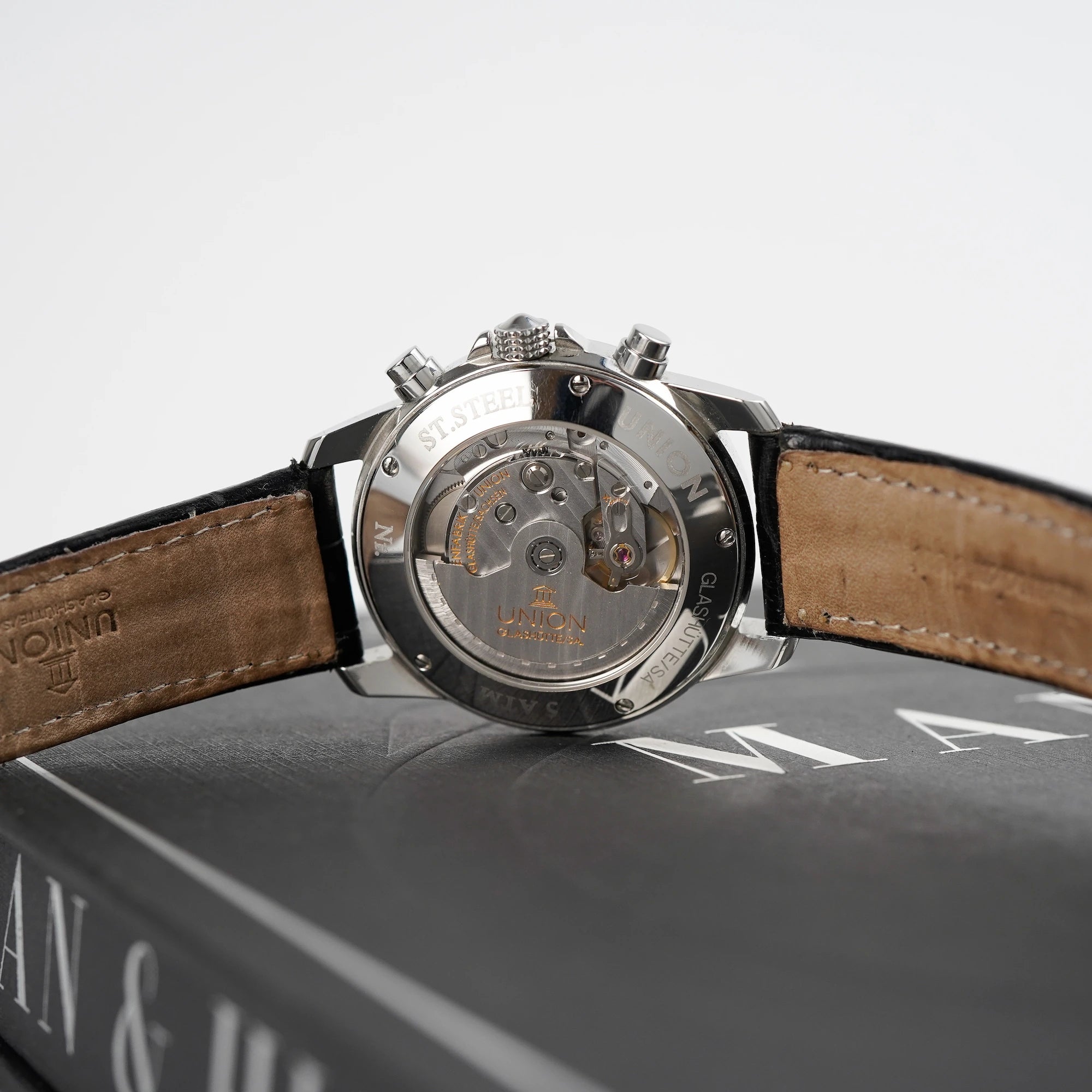 Tradition Chronograph von Union Glashütte liegt auf dem bekannten Uhrenbuch  "A Man & His Watch" und man blickt auf das gläserne Case Back