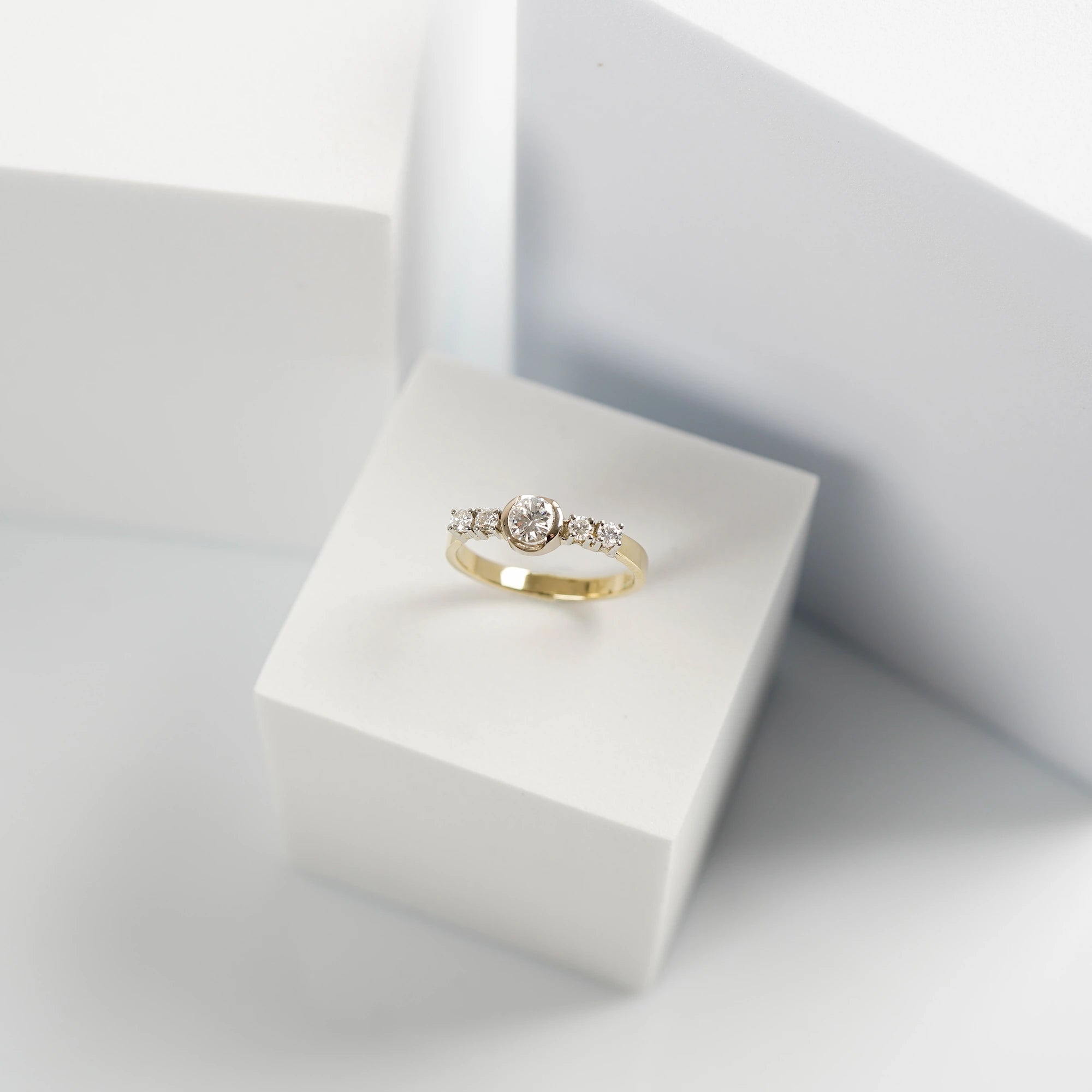 Produktfoto des gelbgoldenen Ring mit 5 gefassten Diamanten auf der Ringschiene, wovon der zentrale Stein der Größte ist