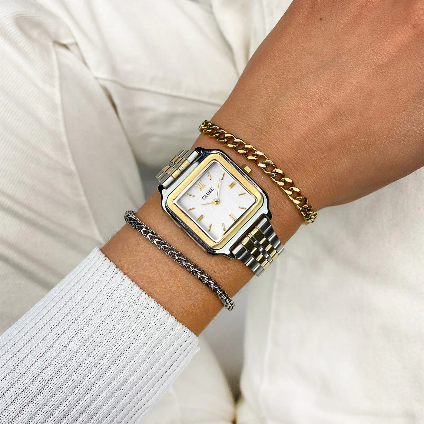 Frau trägt die Cluse Stahl-Uhr "Gracieuse Petite" in Stahl-Gold-Optik (bicolor) mit weißem Zifferblatt und kombiniert diese mit zwei Armbändern