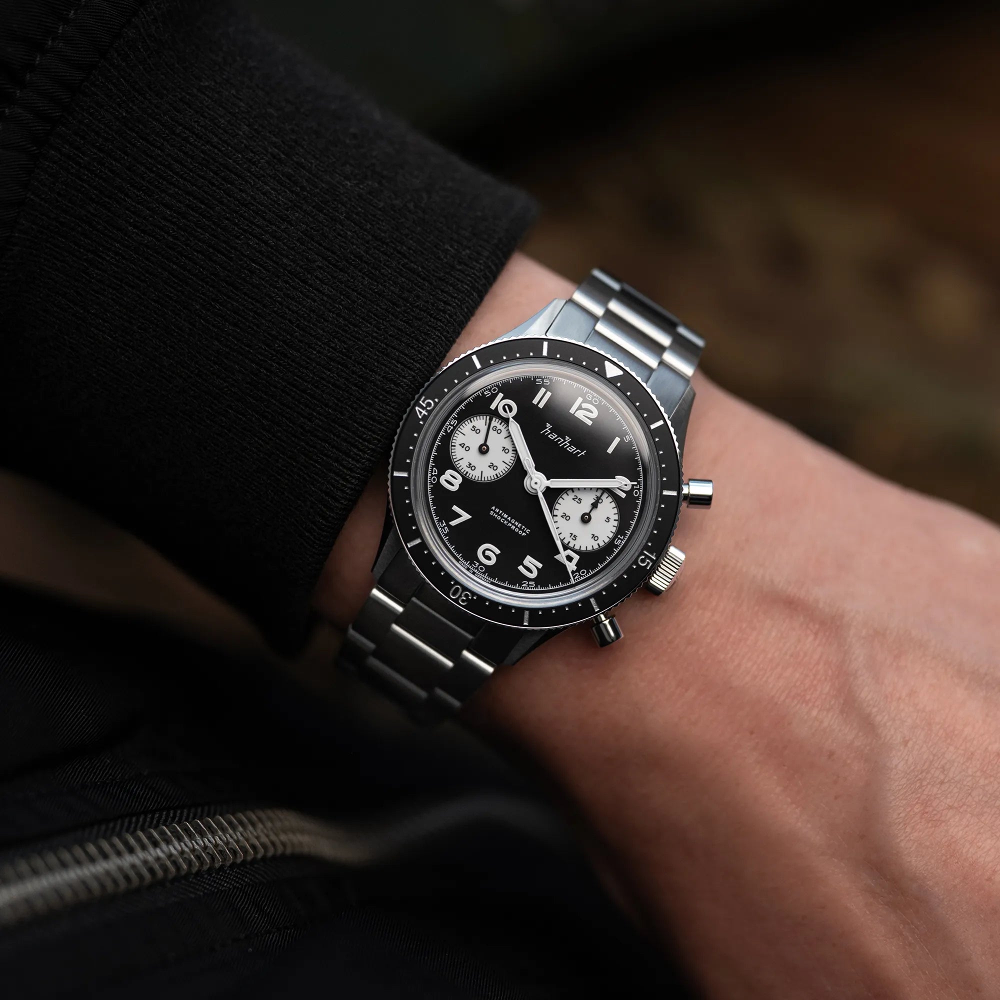 Mann trägt den Hanhart 415 ES Chronograph mit dem Reverse-Panda-Zifferblatt in Schwarz mit weißen Sub-Dials am Edelstahlarmband