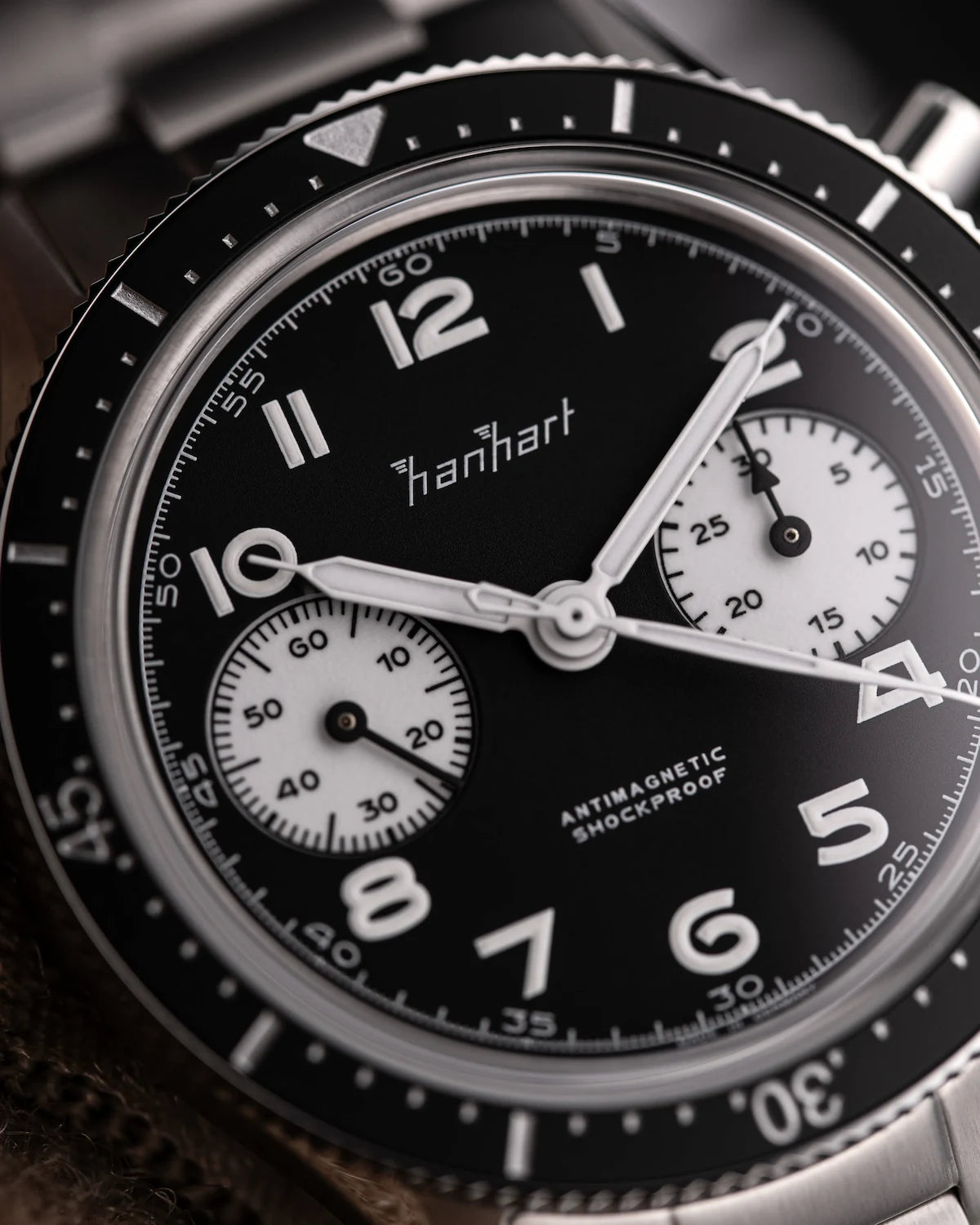 Detailaufnahme des Hanhart 415 ES Chronographs mit dem Reverse-Panda-Zifferblatt in Schwarz mit weißen Sub-Dials am Edelstahlarmband