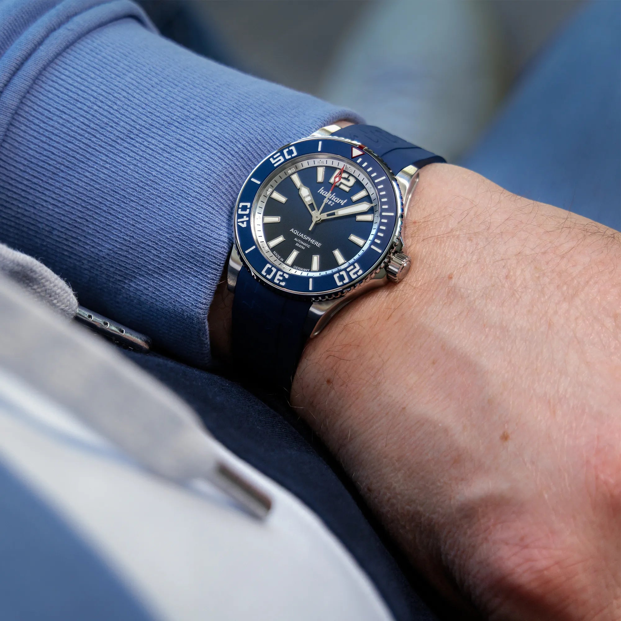 Mann trägt die Hanhart Aquasphere mit dem blau-schwarz verlaufenden "Ocean Fade"-Zifferblatt und blauem  Keramik-Inlay auf der Lünette am Edelstahlarmband am Handgelenk