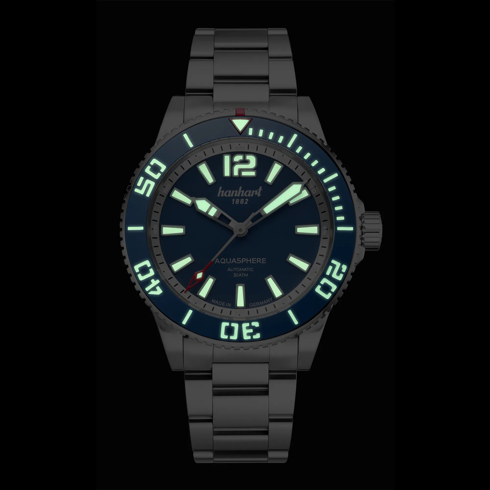 Frontale Ansicht der Hanhart Aquasphere mit dem blau-schwarz verlaufenden "Ocean Fade"-Zifferblatt und blauem  Keramik-Inlay auf der Lünette am Edelstahlarmband bei Nacht mit aktivierter Lreuchtmasse