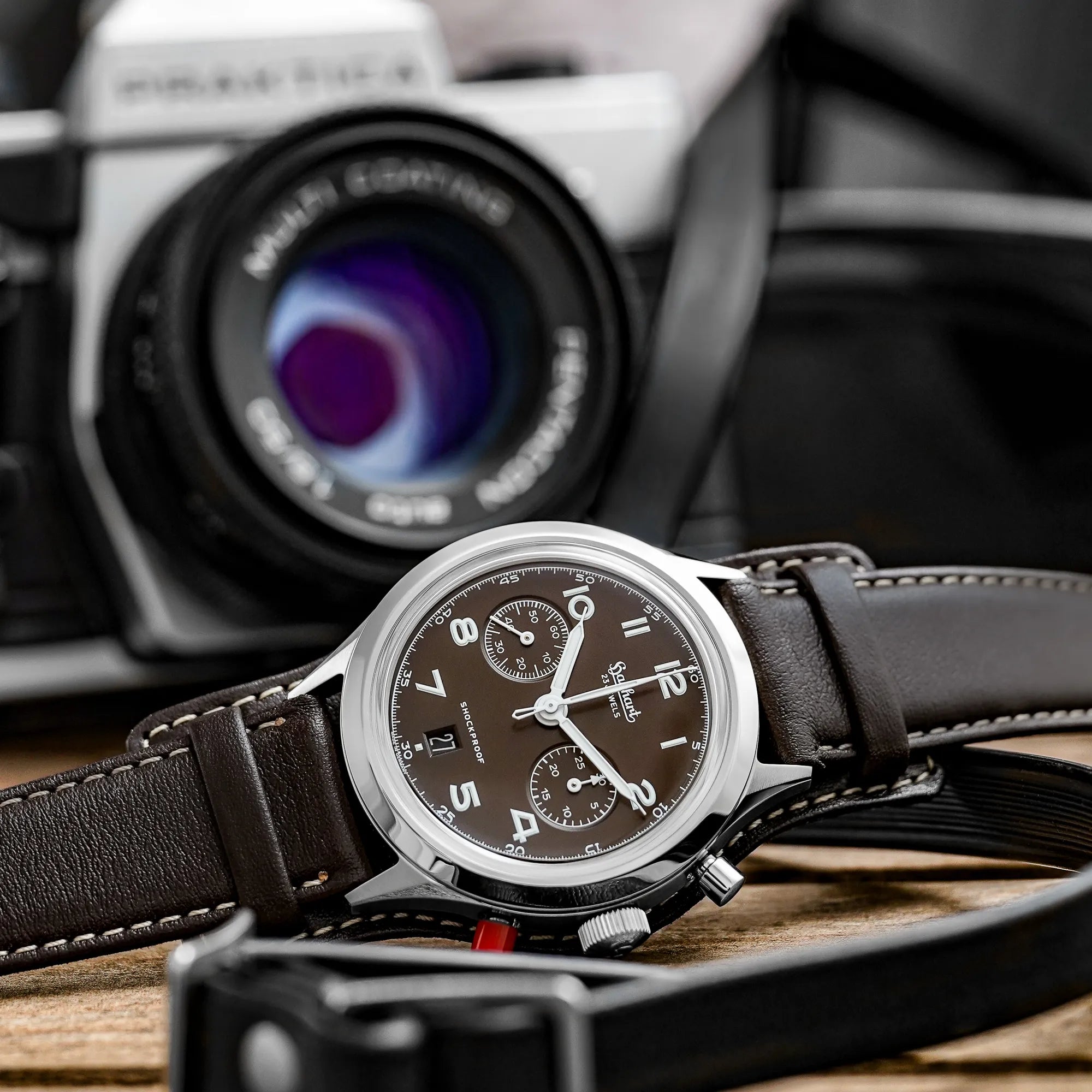 Produktfotografie der Hanhart 417 ES Mokka Limited Edition mit einem braunem Zifferblatt an einem passenden braunem Lederband mit Unterlage