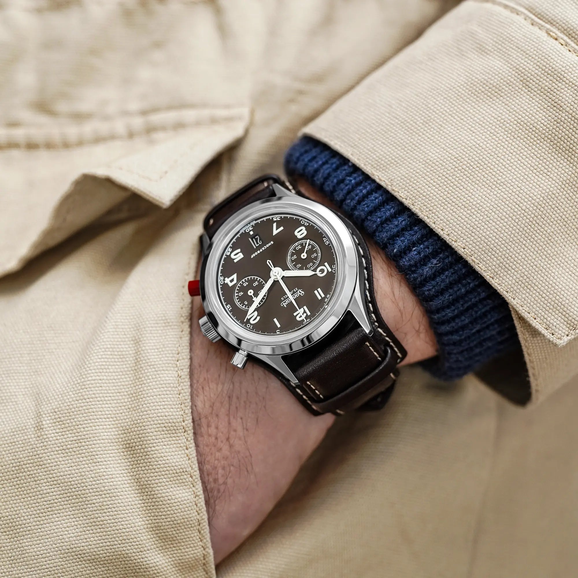 Mann trägt die Hanhart 417 ES Mokka Limited Edition mit einem braunem Zifferblatt an einem passenden braunem Lederband mit Unterlage an seinem Handgelenk