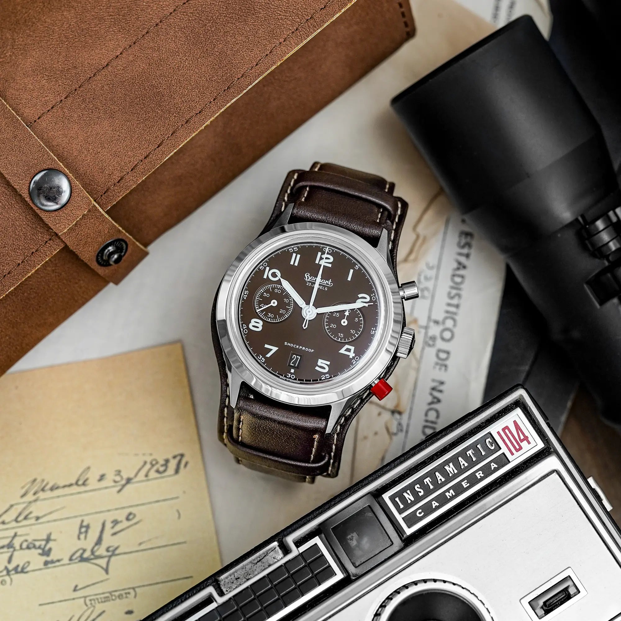 Produktfotografie der Hanhart 417 ES Mokka Limited Edition mit einem braunem Zifferblatt an einem passenden braunem Lederband mit Unterlage