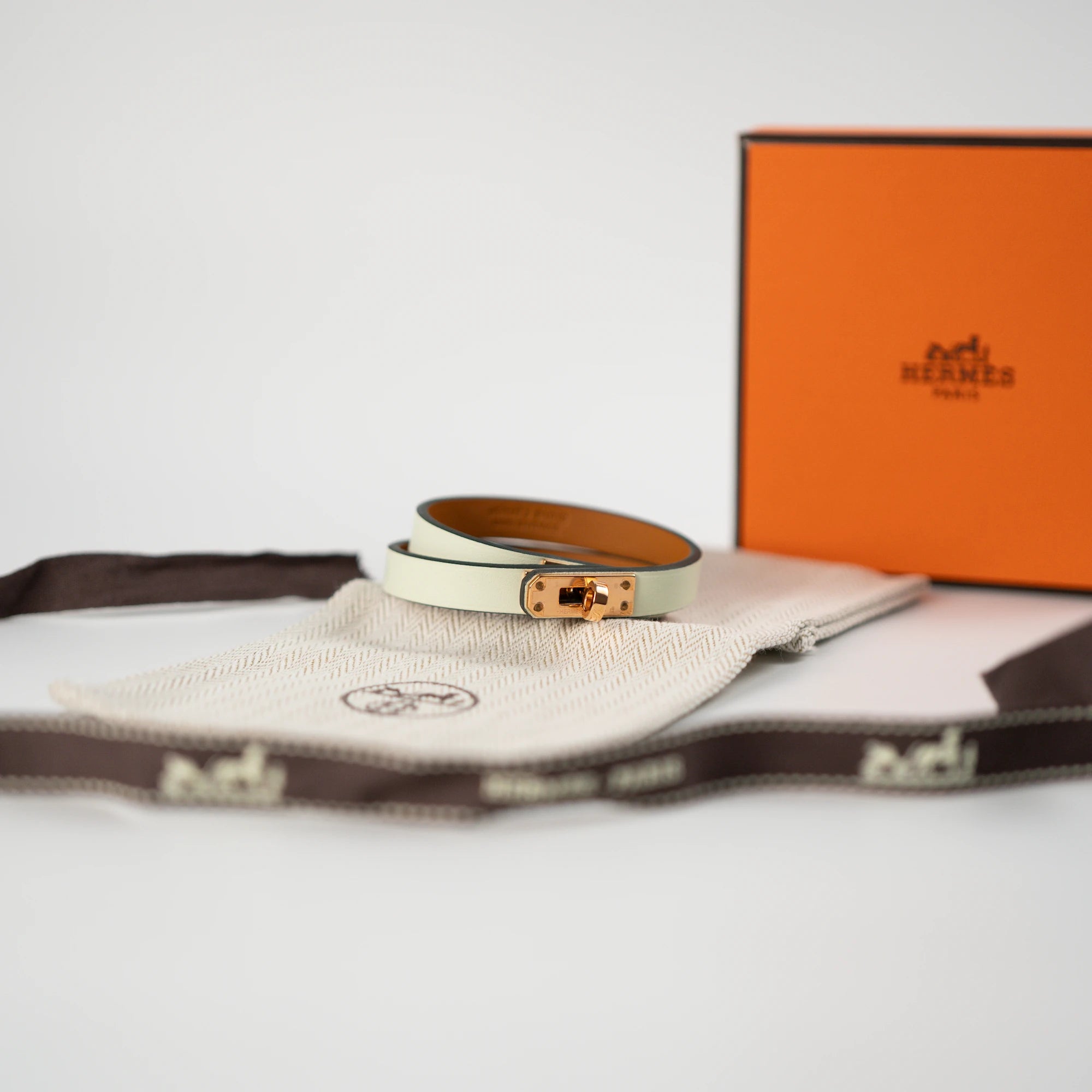 Produktfotografie des Türkises Leder-Armband "Mini Kelly Double Tour" von Hermès mit rosegoldenem Verschluss zusammen mit dem Lieferumfang