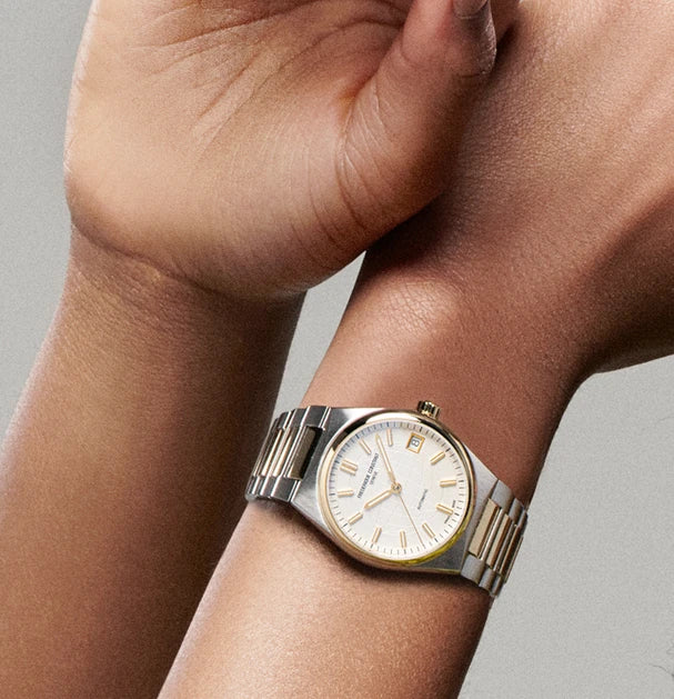 Frau trägt die Frederique Constant Highlife Ladies Automatic mit 34mm Durchmesser in der Stahl-Gold-Variante mit dem weißen Zifferblatt an ihrem Handgelenk