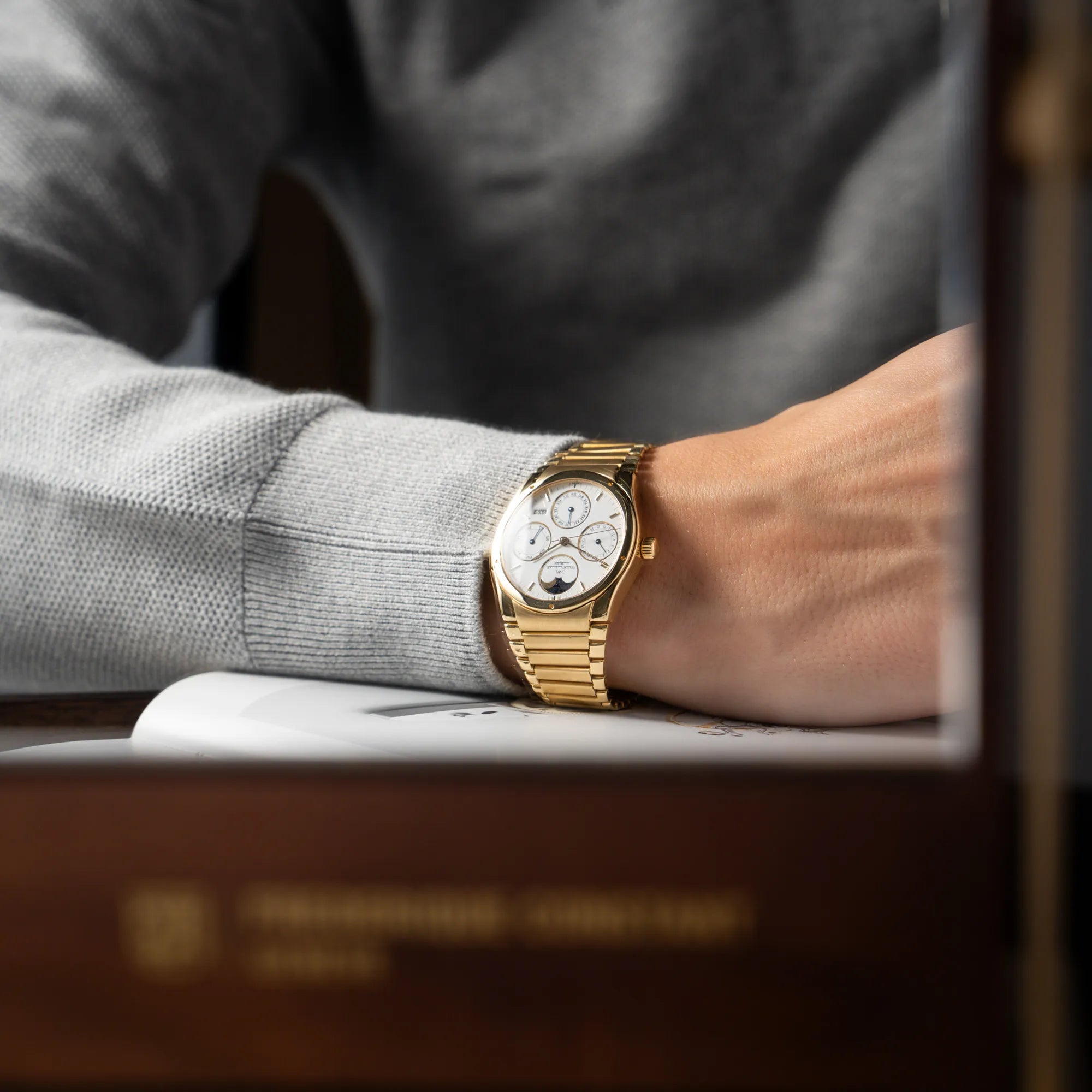 Mann mit grauem Pullover trägt die IWC Ingenieur Perpetual Calendar in Gelbgold mit weißem Zifferblatt und zughörigem Gelbgold-Armband an seinem Handgelenk