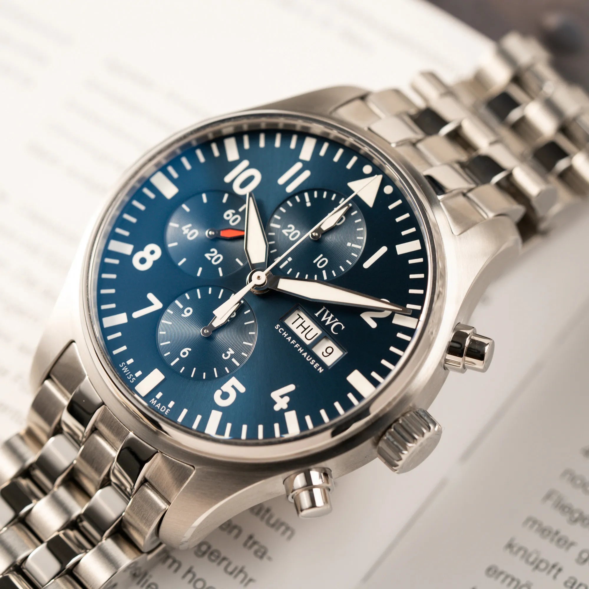 Detailreiche Produktfotografie des IWC Pilot Chronograph "Le Petit Prince" IW377717 mit 43 mm Gehäuse und blauem Zifferblatt am Edelstahl-Armband