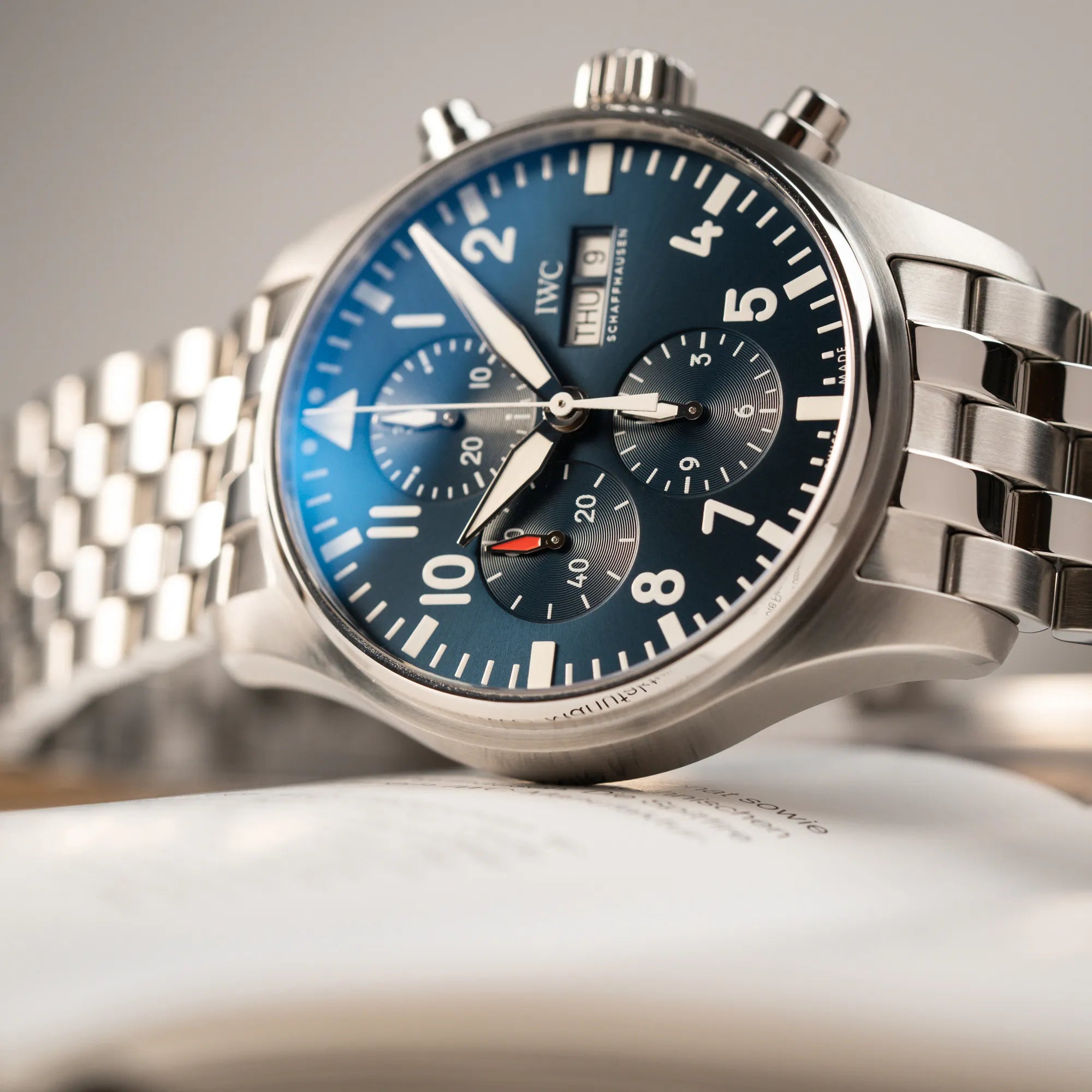 Nahaufnahme des seitlich auf dem Gehäuse liegenden IWC Pilot Chronograph "Le Petit Prince" IW377717 mit 43 mm Gehäuse und blauem Zifferblatt am Edelstahl-Armband