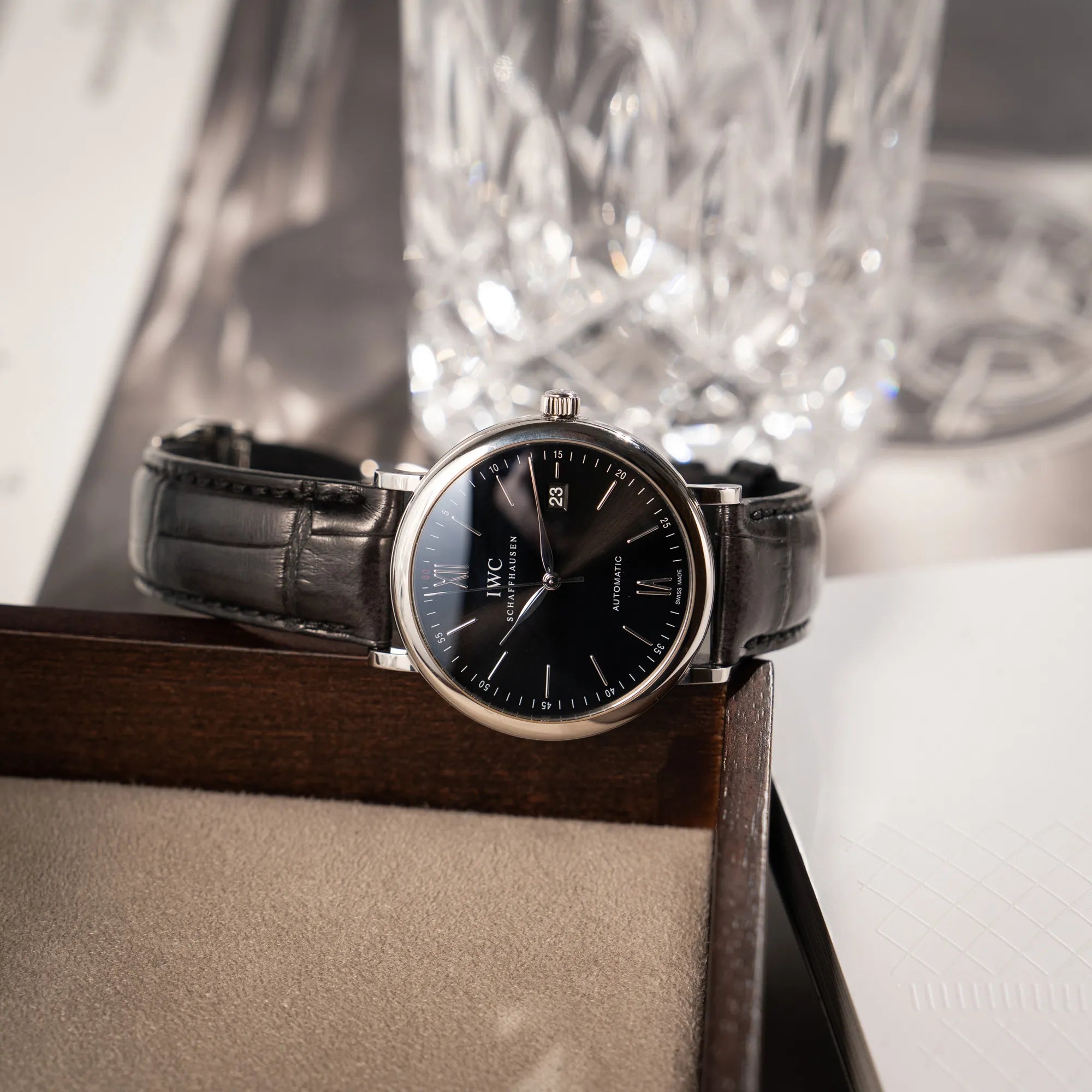 Produktfotografie der IWC Portofino 40 Automatik Armbanduhr mit schwarzem Zifferblatt am schwarzen Lederband während die Uhr auf einem Juwelierstablet liegt