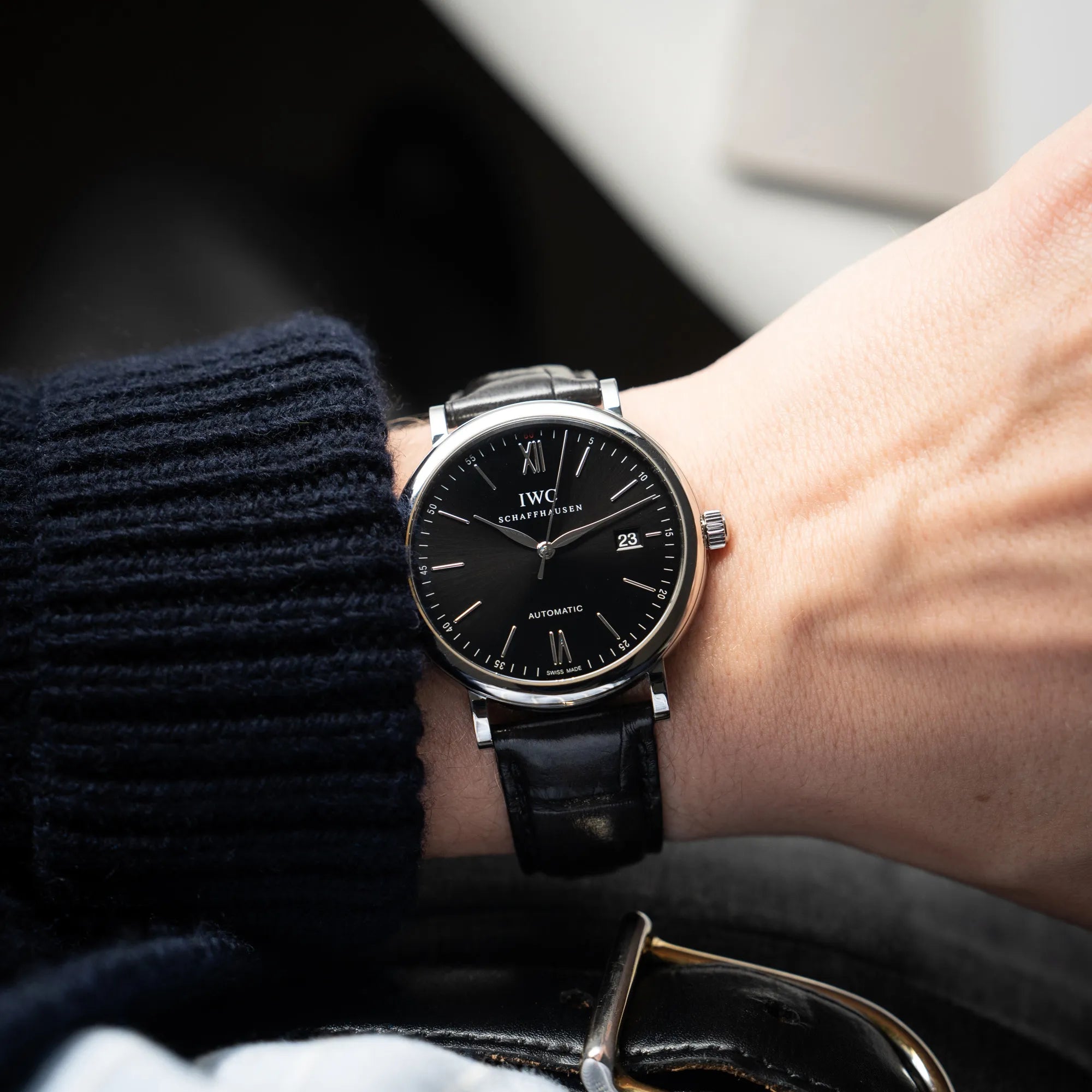 Mann trägt die IWC Portofino 40 Automatik Armbanduhr mit schwarzem Zifferblatt am schwarzen Lederband für einen Wristshot an seinem Handgelenk